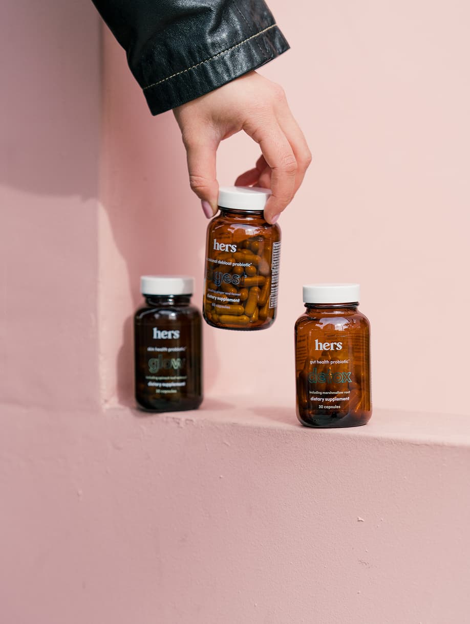 Hers wellness supplement bottles on pink background