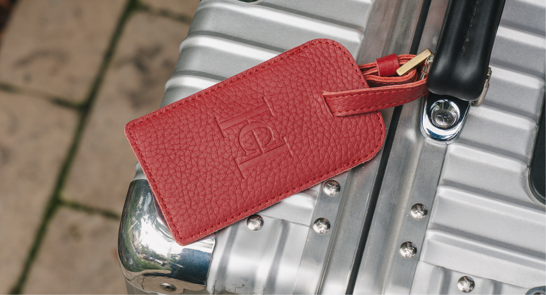 Custom red embossed leather luggage tag on suitcase
