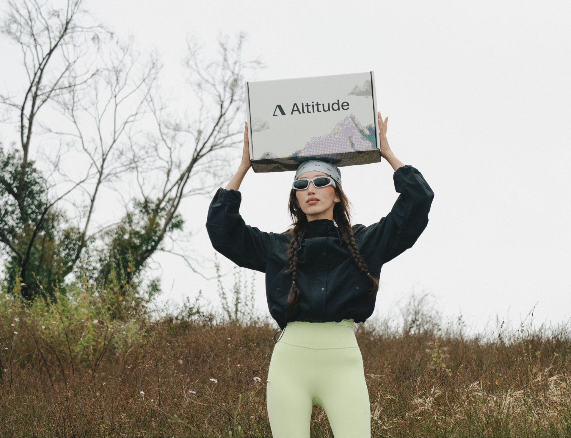 Model outside holding an Altitude branded packaging mailer box