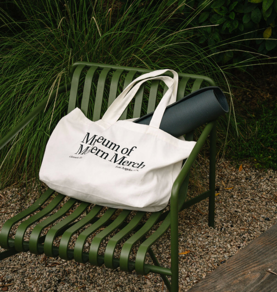 MOMA branded tote with yoga mat on green chair outside