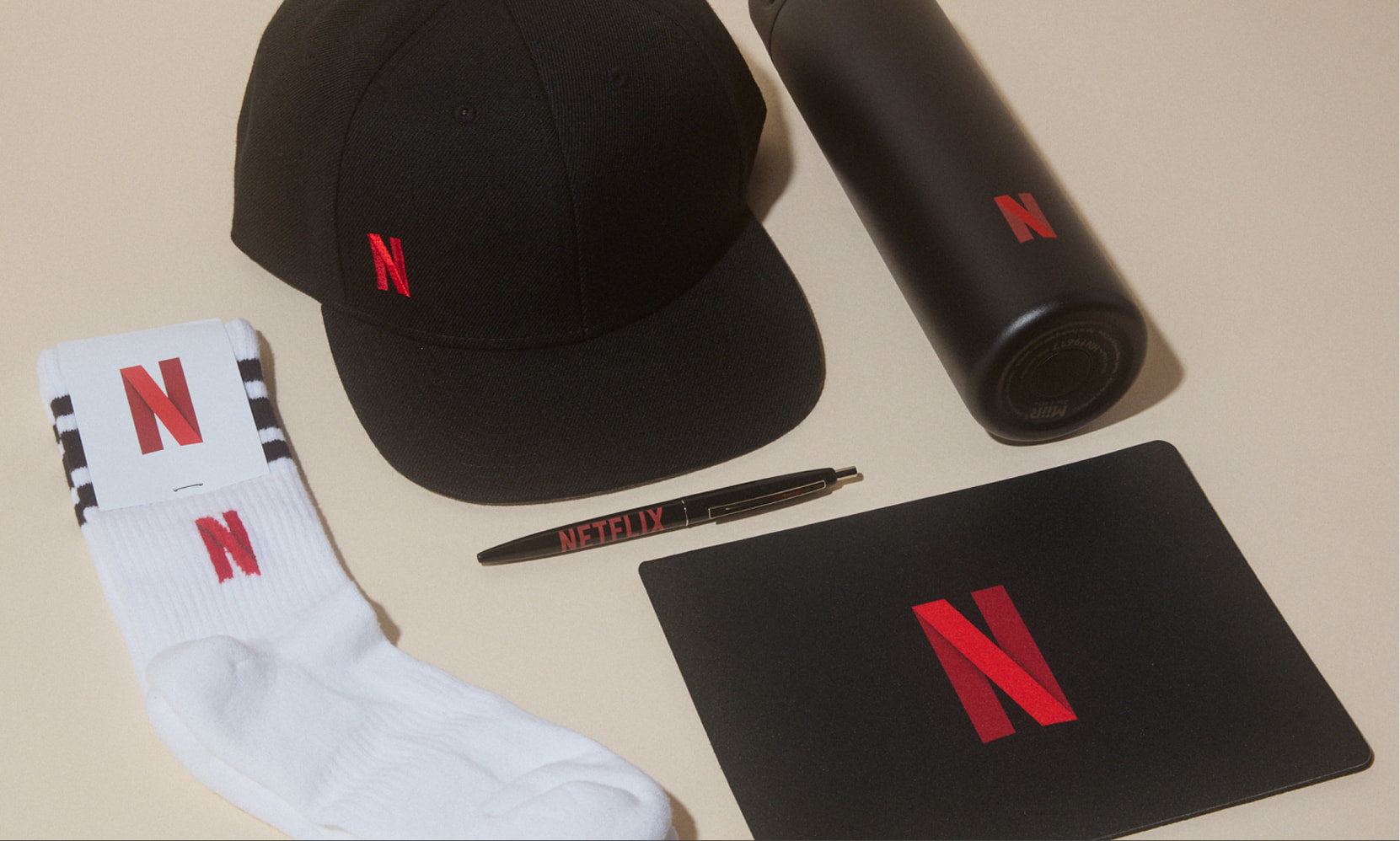 Custom Netflix swag including branded white socks, black pen, cap, bottle and notepad