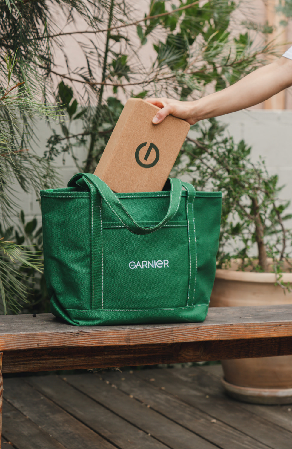 Model placing branded kraft box inside Garnier branded green tote bag