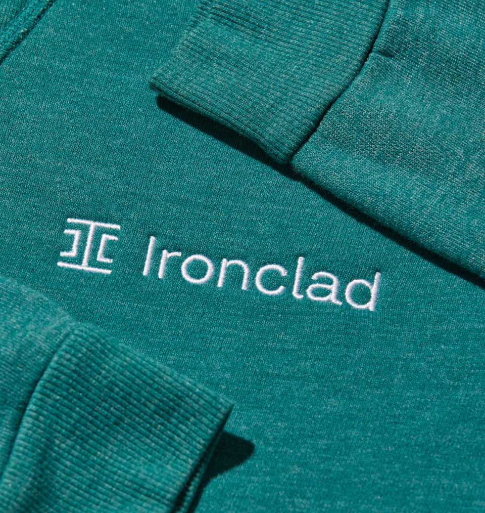 Closeup of Ironclad white logo embroidered on teal sweatshirt