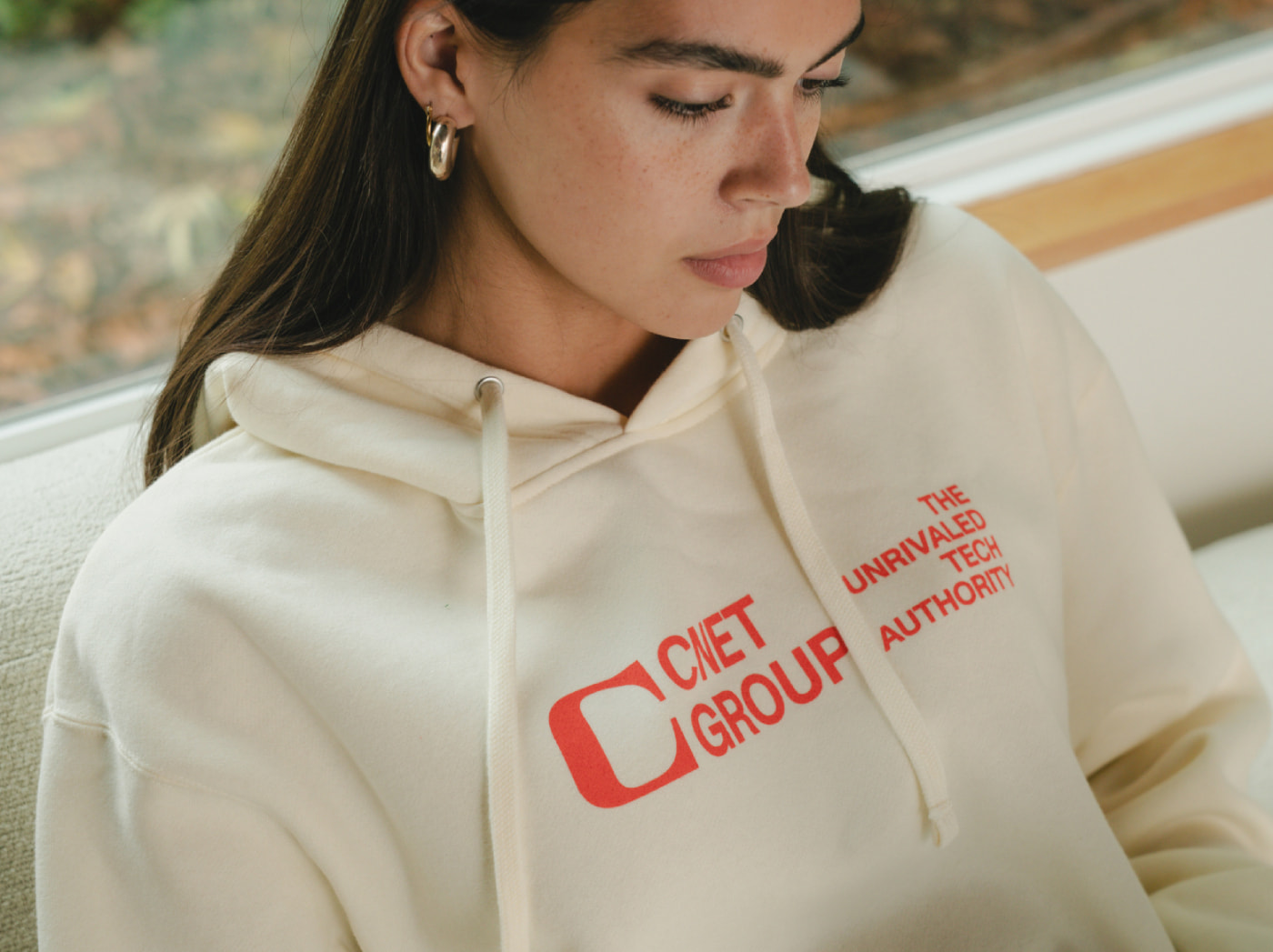 Closeup of model wearing white hoodie with orange CNET Group screen print logo