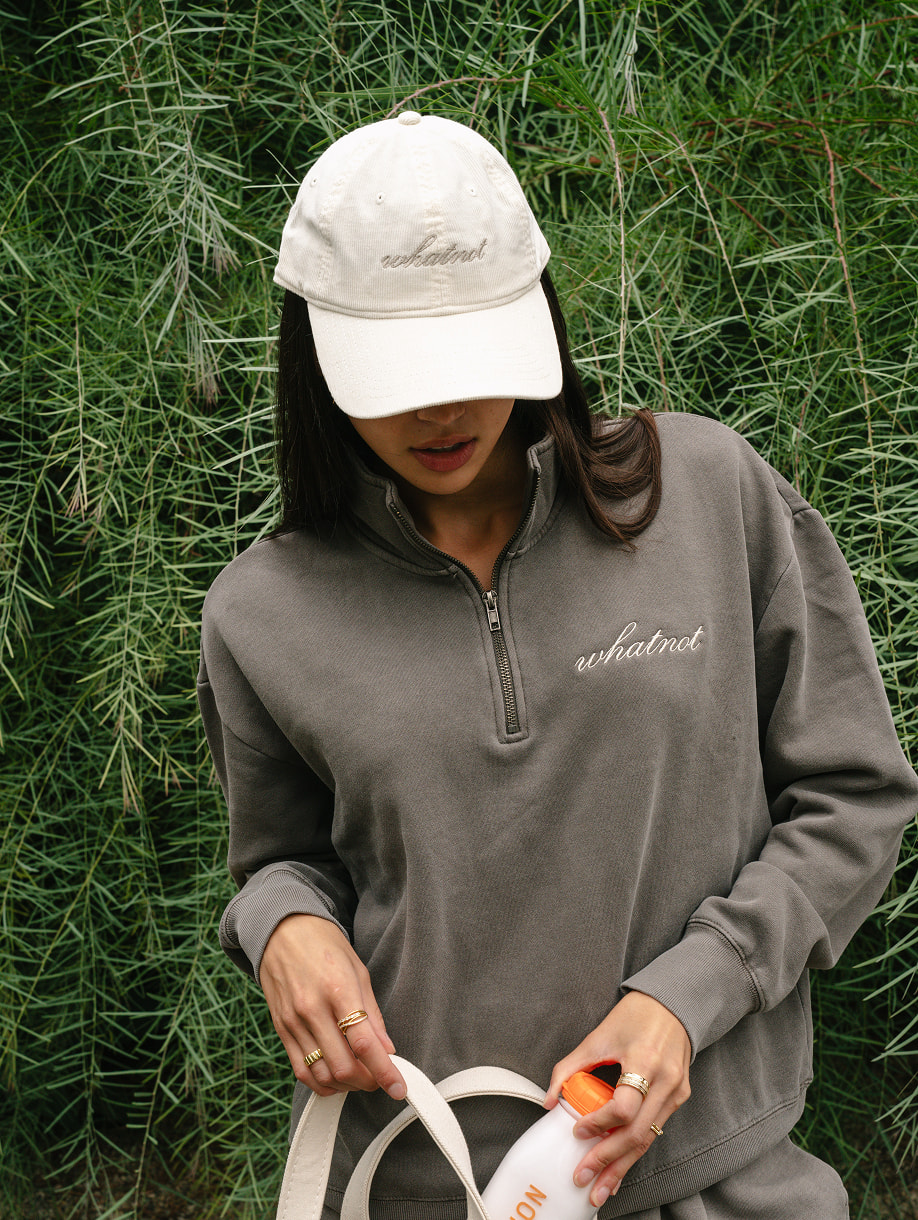 Whatnot custom gray quarter-zip sweatshirt and white cap on model