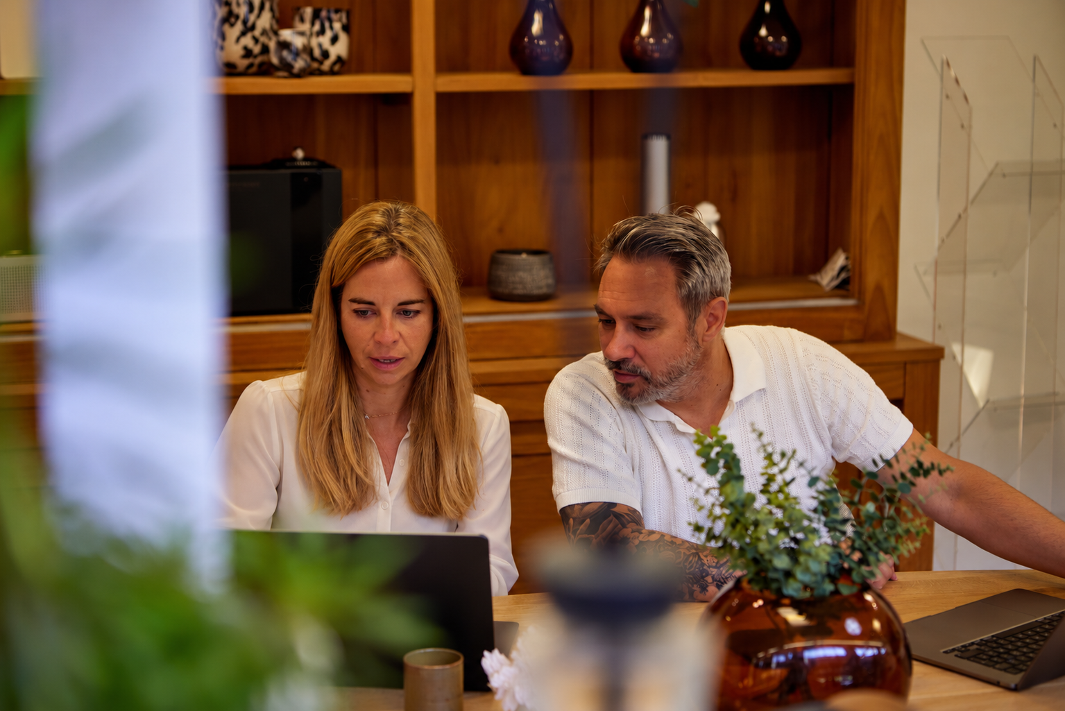 Twee medewerkers van Emoliquids overleggen aan een laptop in de showroom
