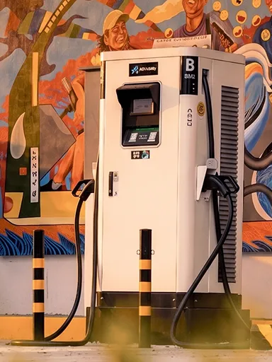 ACMobility DC fast charger beside a painted mural.