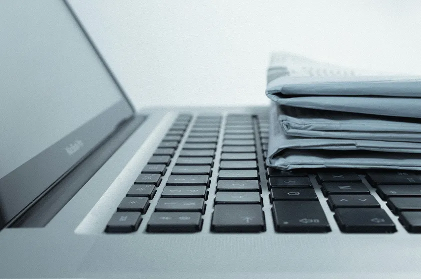 Close-up of a laptop keyboard with folded documents stacked on it.