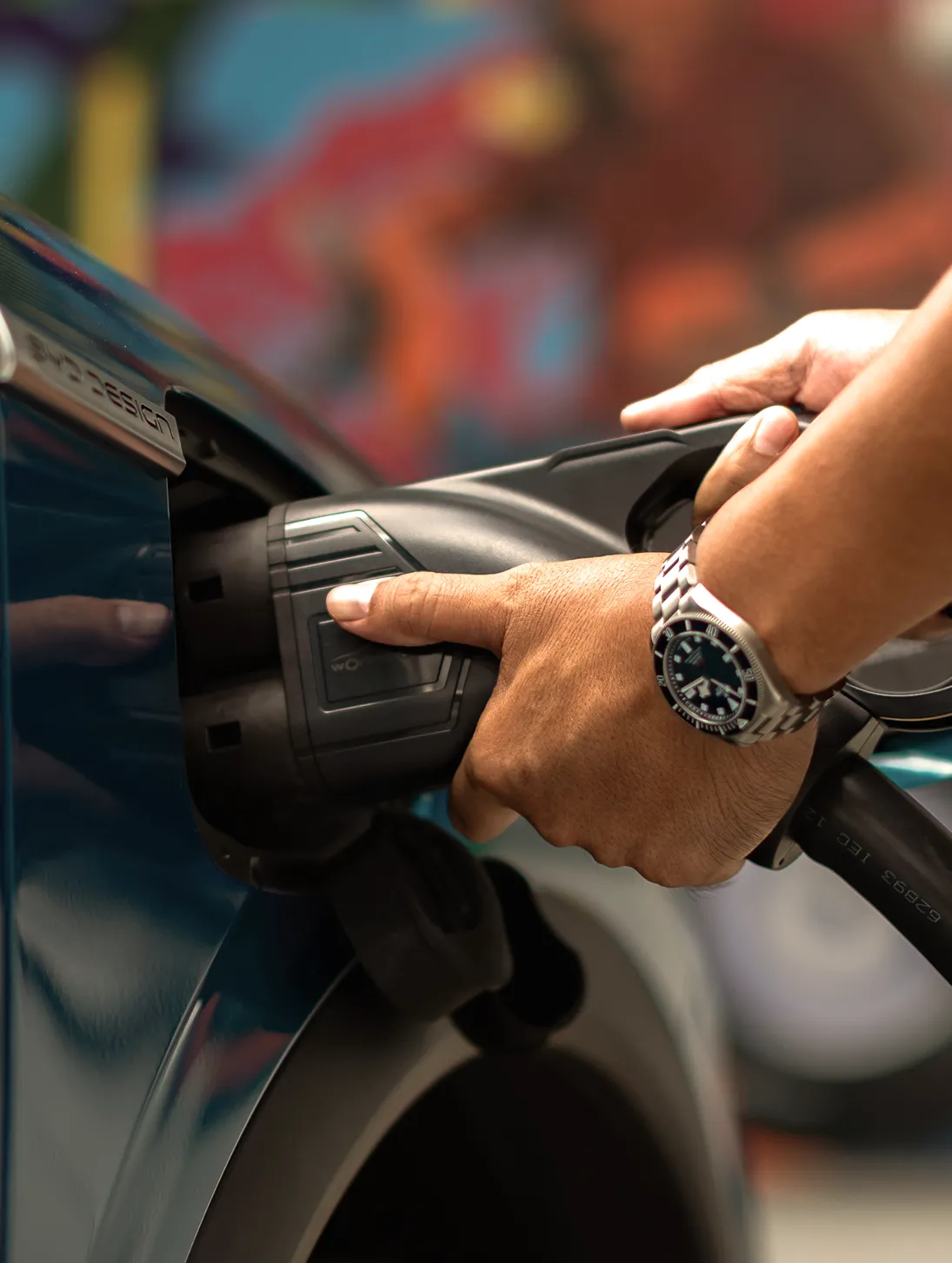 Hand plugging a charger into an electric vehicle.