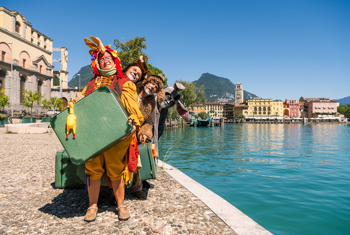 Quattro persone in costumi animali con Riva del Garda sullo sfondo