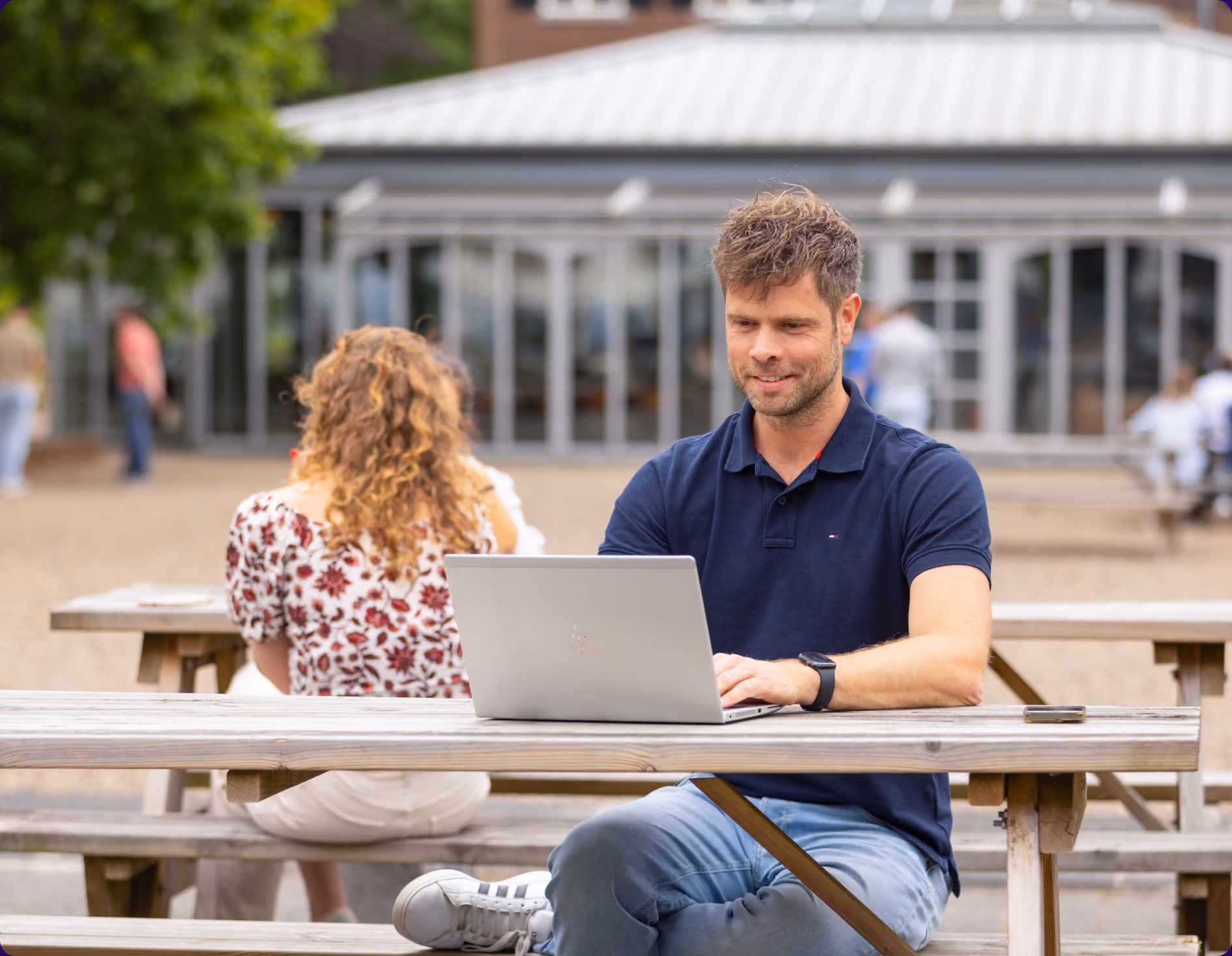 BBTG-collega werkt buiten aan een picknicktafel op zijn laptop