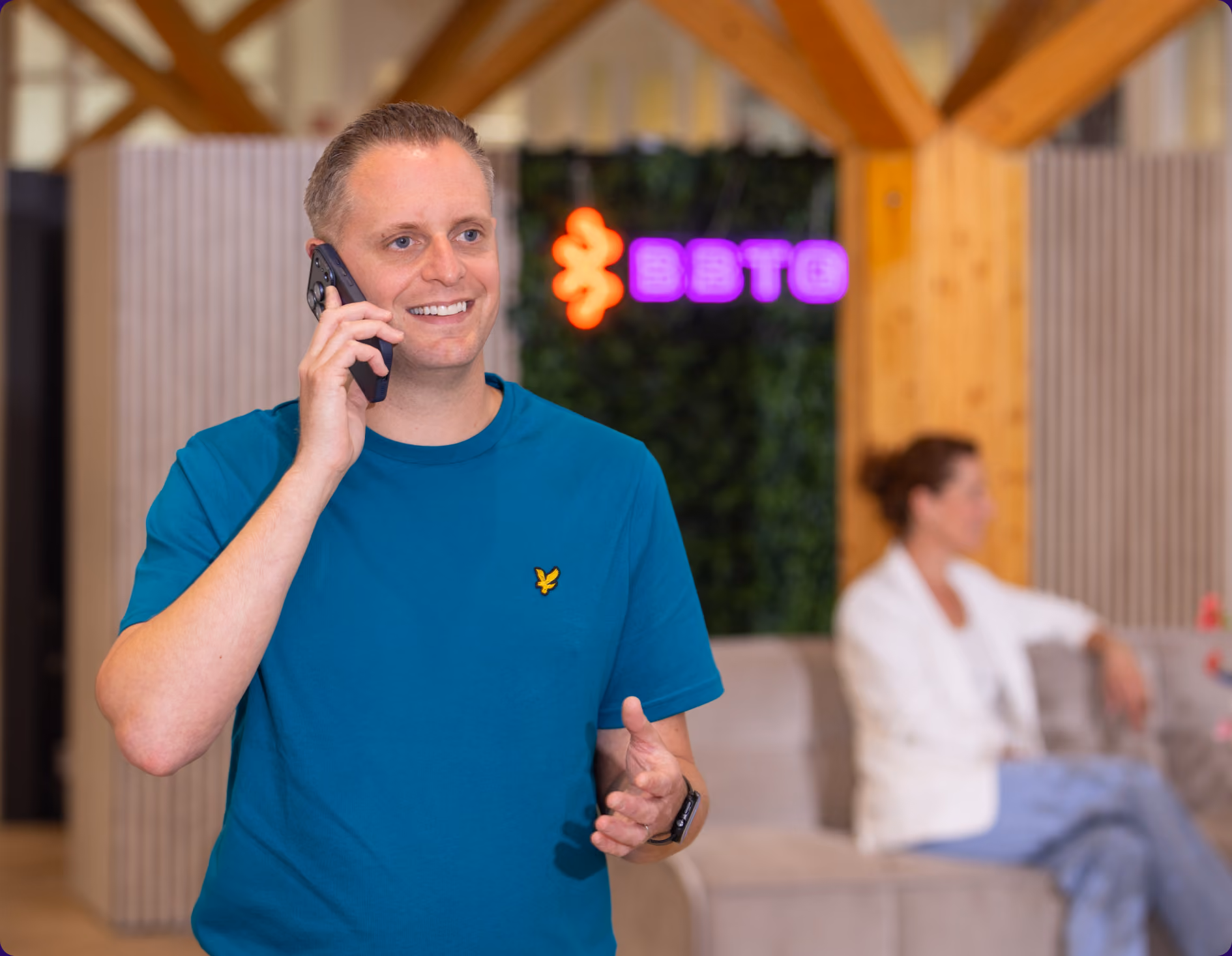 BBTG-collega belt in de lounge onder het BBTG-neonlogo