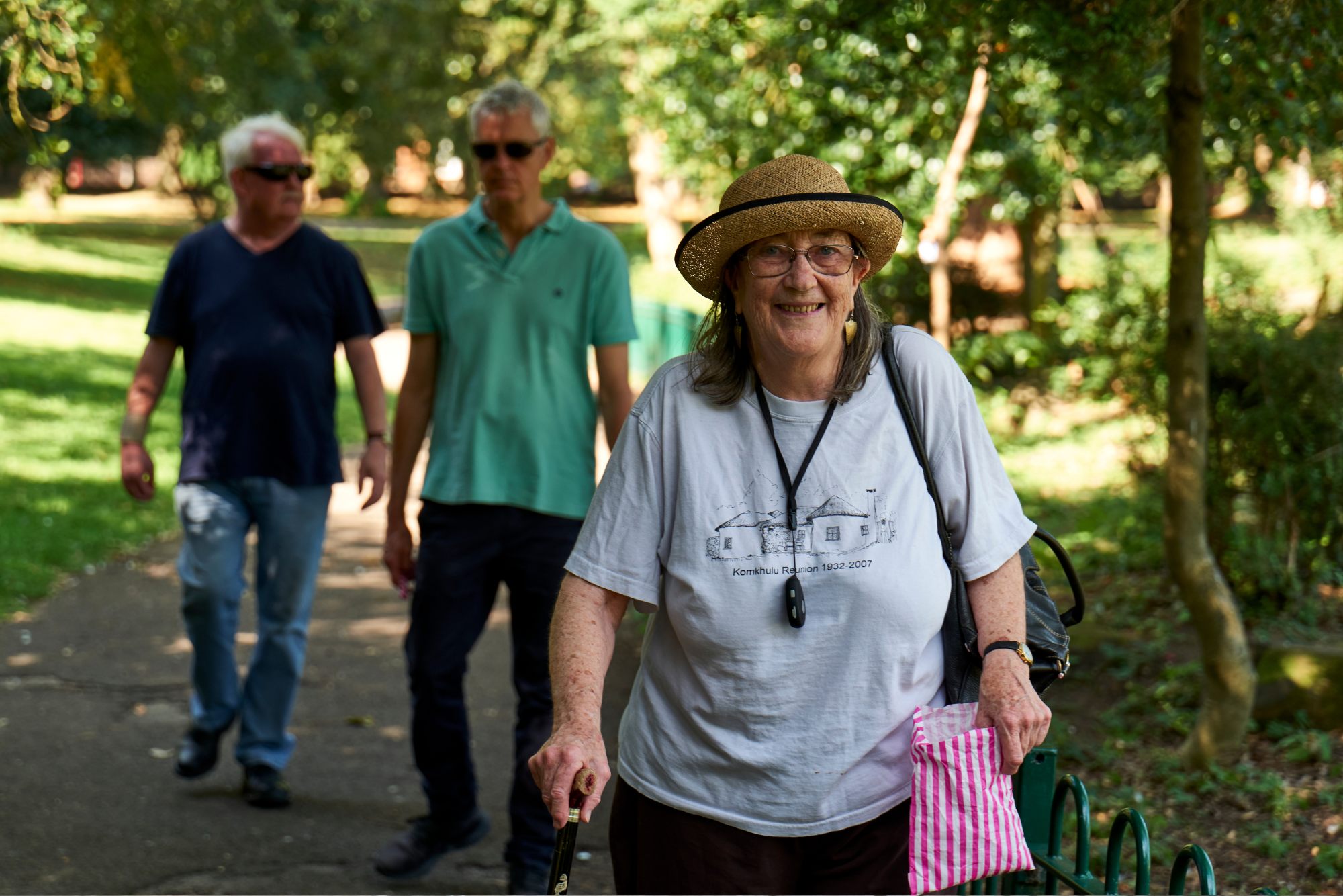 Woman with walking stick walking through park
