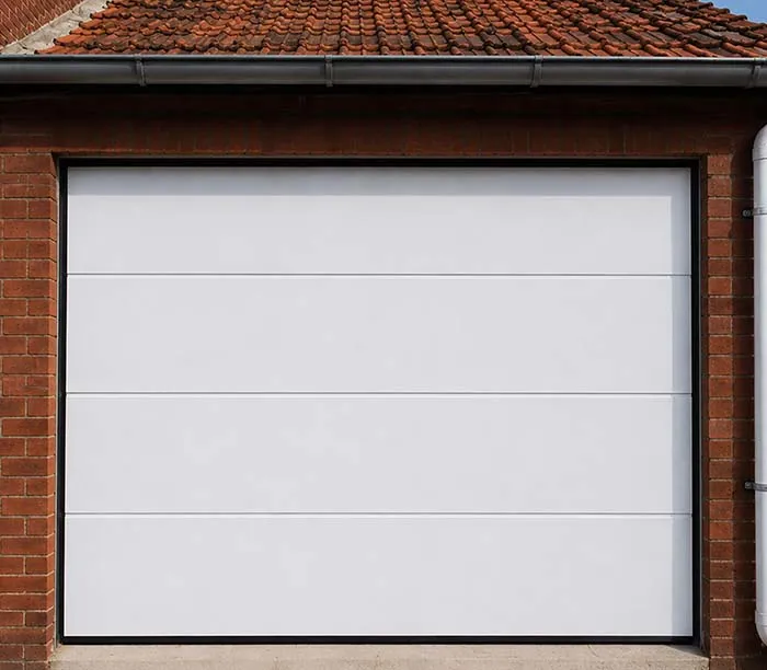 Porte de garage blanche sectionnelle sur une maison en briques avec toit en tuiles rouges.