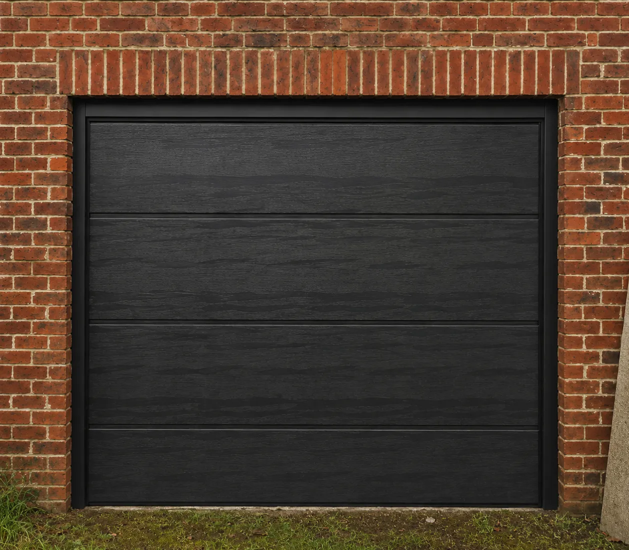 Porte de garage noire à panneaux horizontaux encadrée de briques rouges.