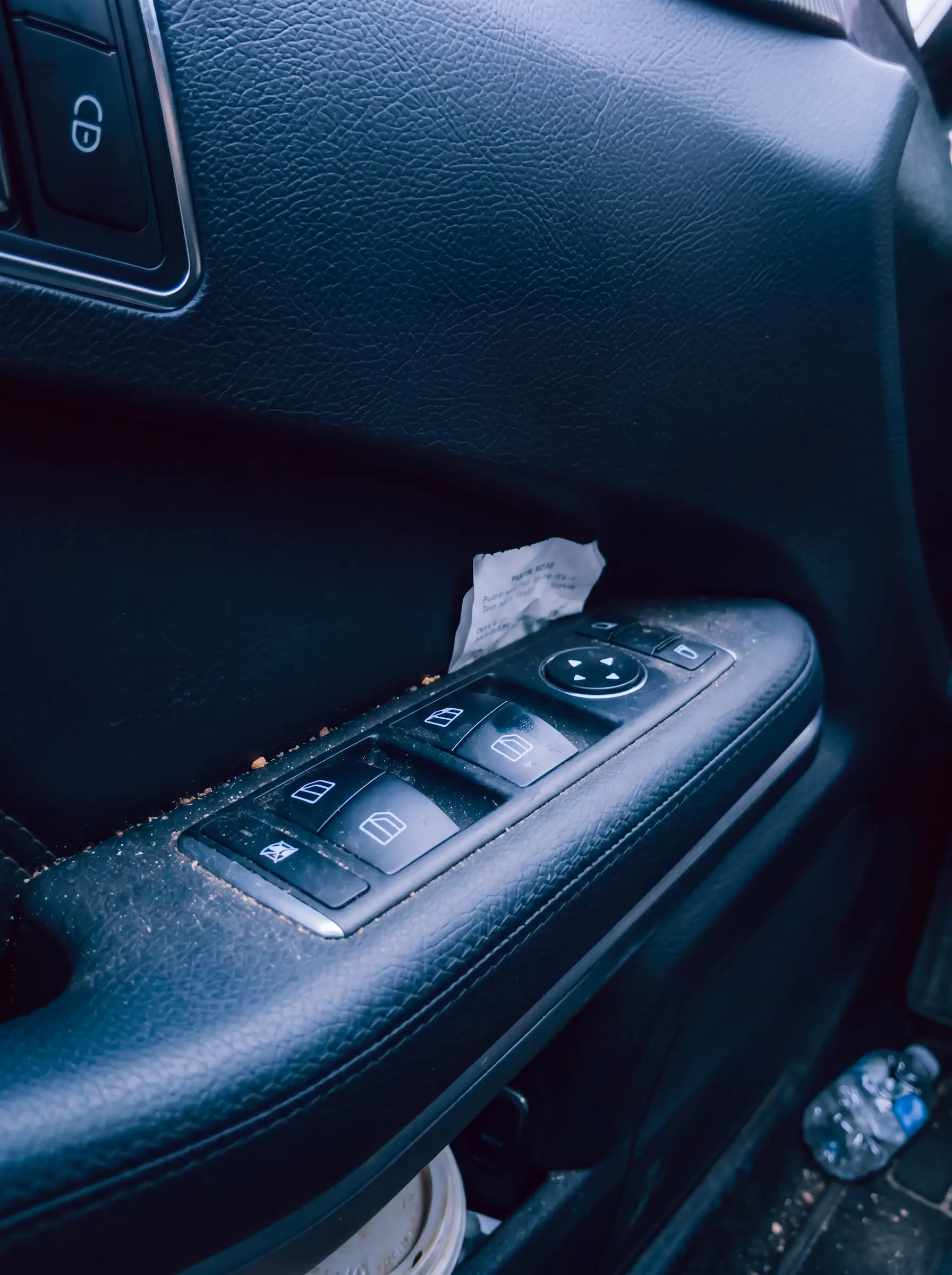 Dirty car door control panel with window switches and a mirror adjustment joystick.