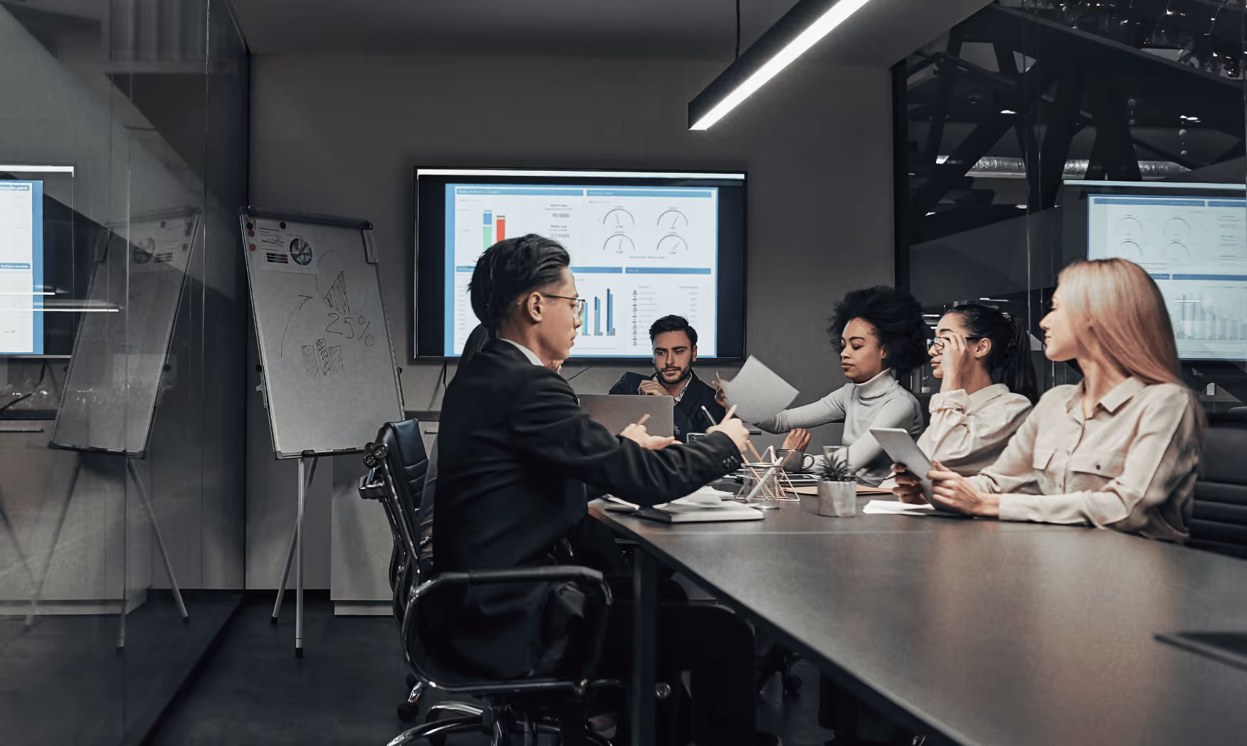 Business team discussing charts and data on screen during a meeting in a modern conference room.