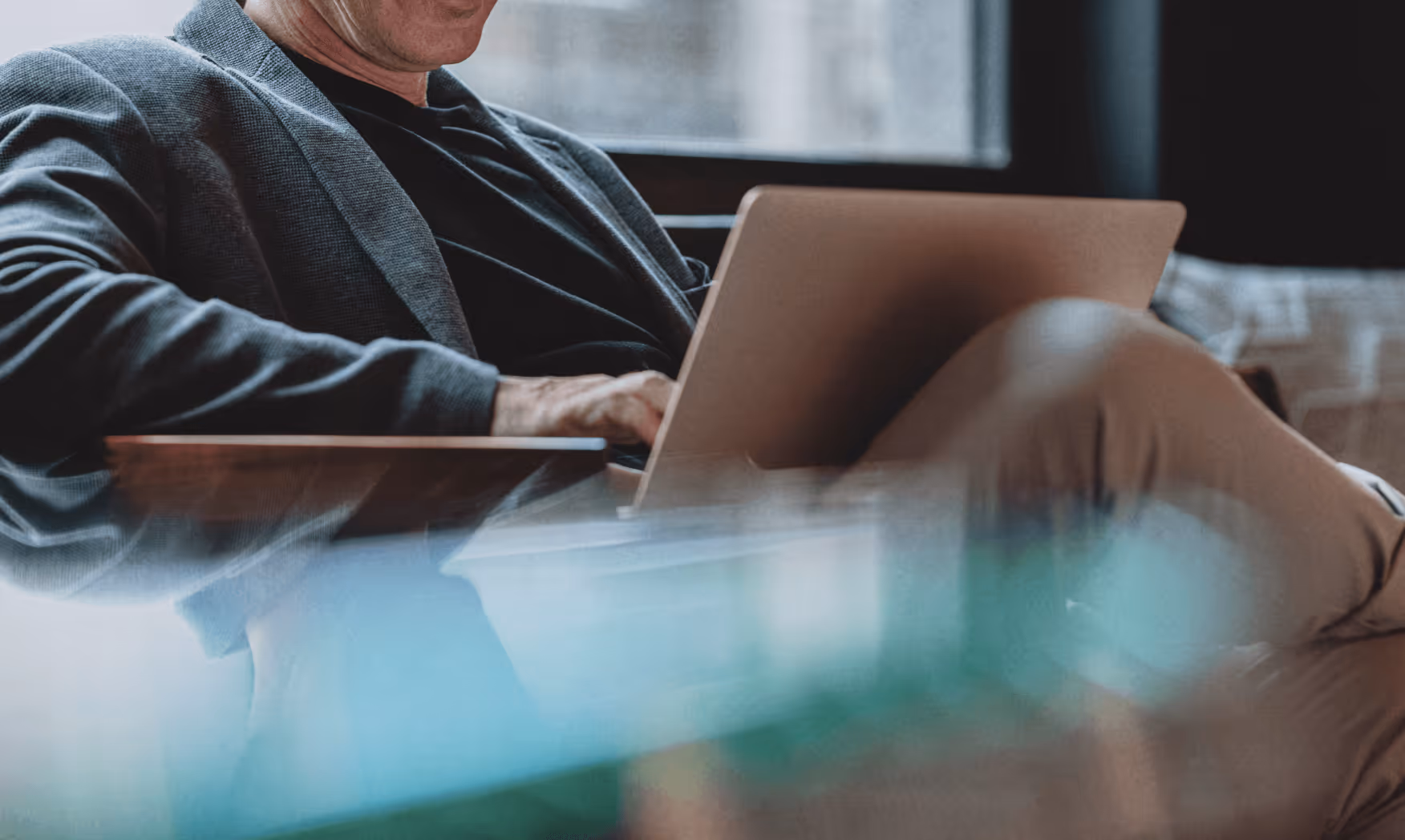 Man sitting and working on a laptop in a cozy, softly lit indoor space.