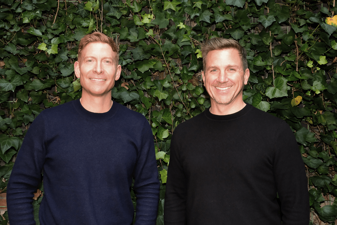 Foresight co-founders standing side by side, smiling, in front of a green ivy wall.