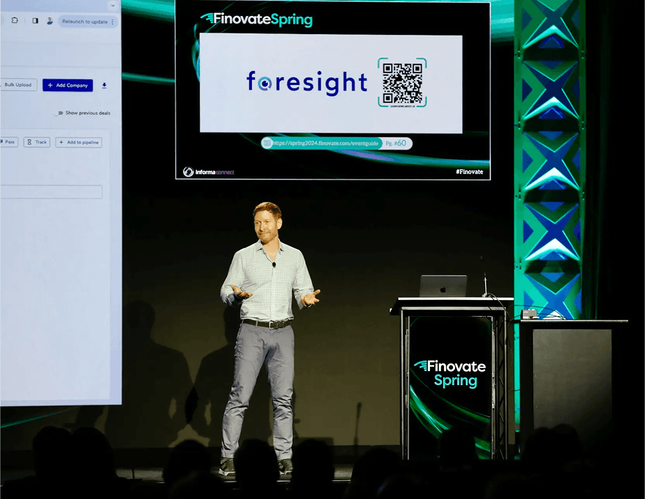 A Foresight speaker presenting on stage at FinovateSpring, with a large screen behind them displaying the Foresight logo.
