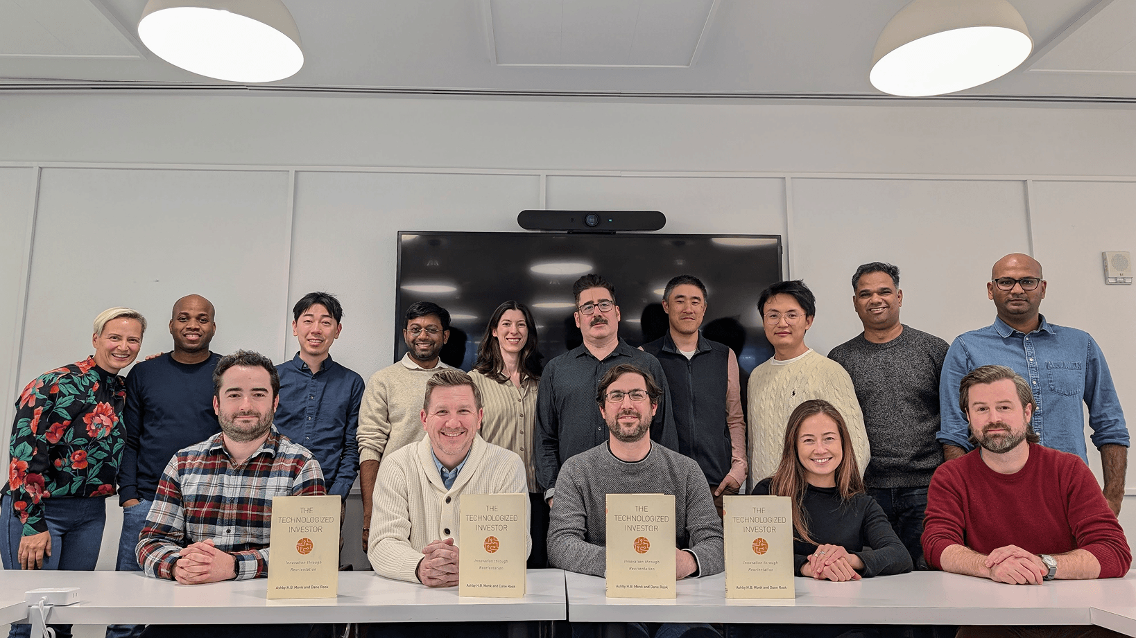 Foresight team in a conference room; four people seated in front hold copies of the book "The Technologized Investor."