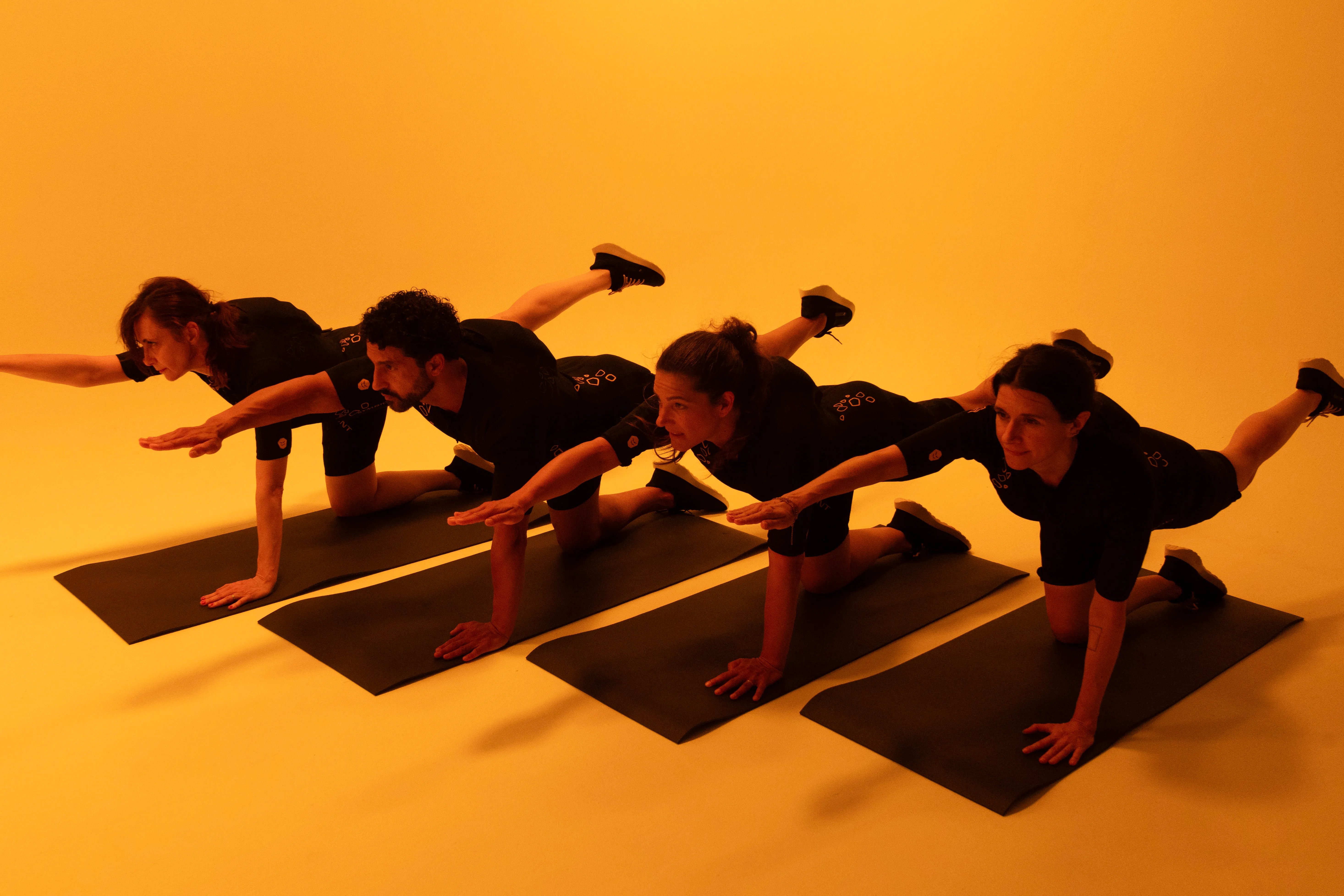 Groupe réalisant un exercice de gainage en équilibre sur tapis