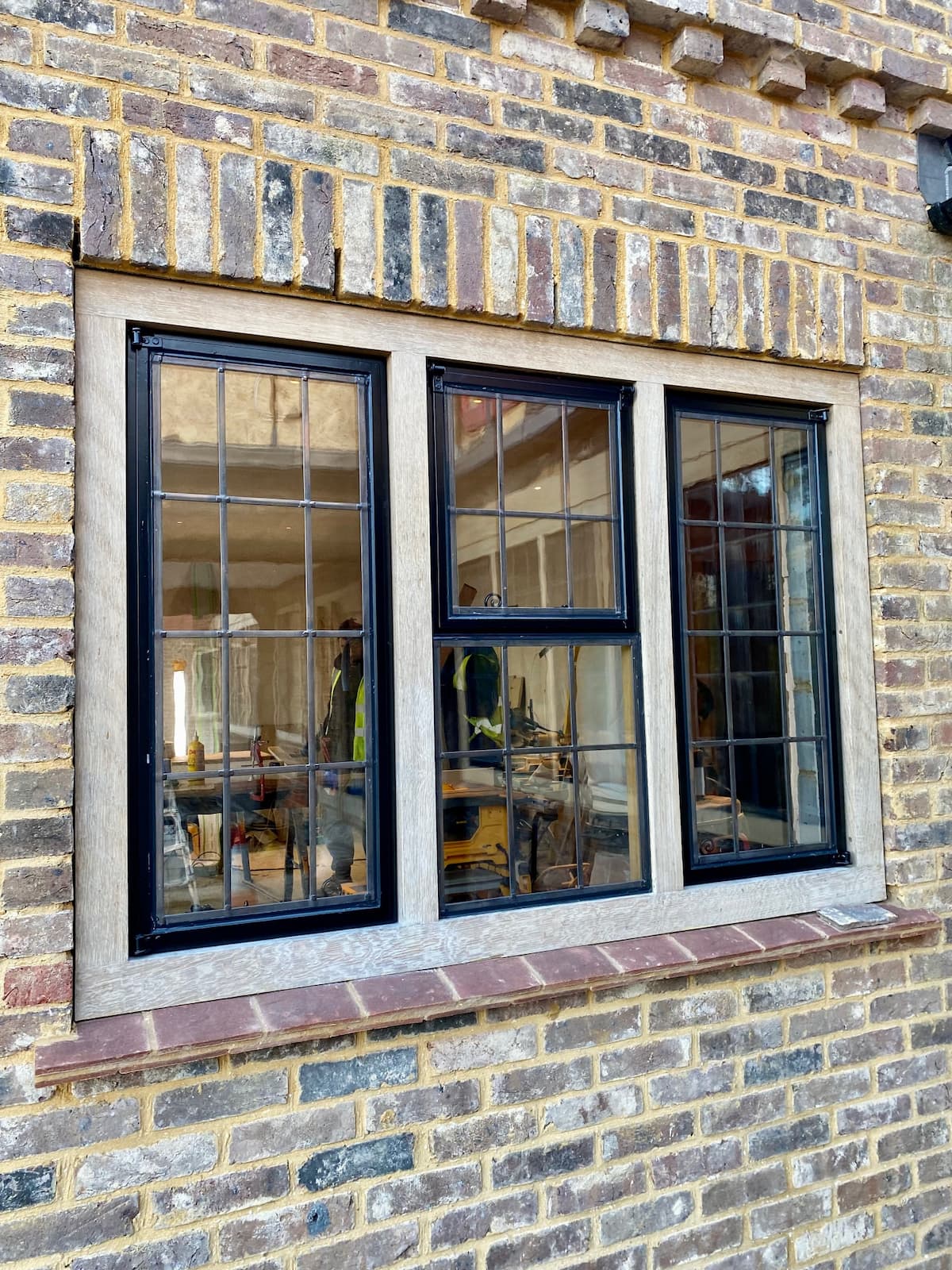 Close up of a wooden window frame on the side of a red brick house.