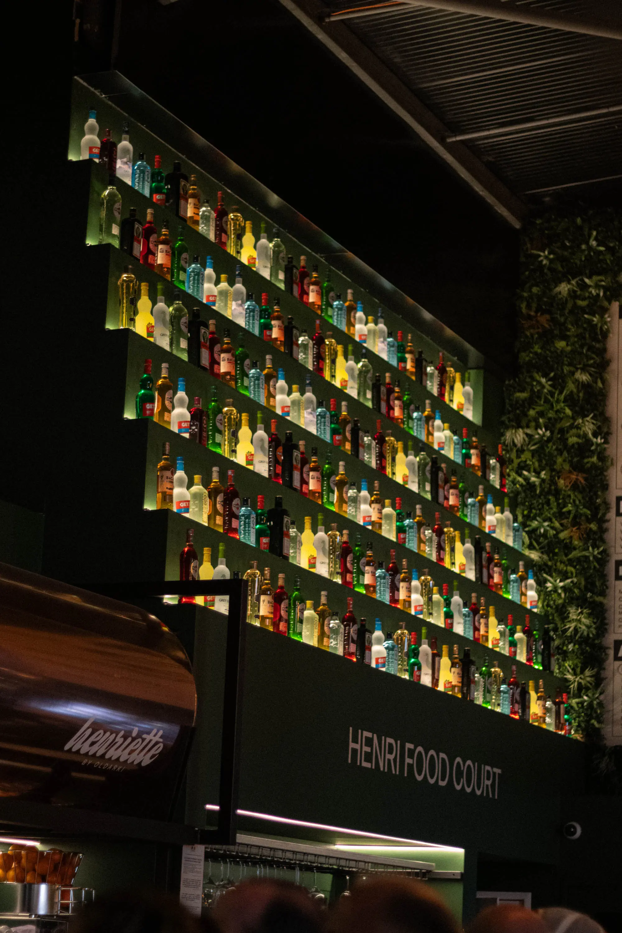 Mur de bouteilles rétroéclairé du bar Henri Food Court à Lescar