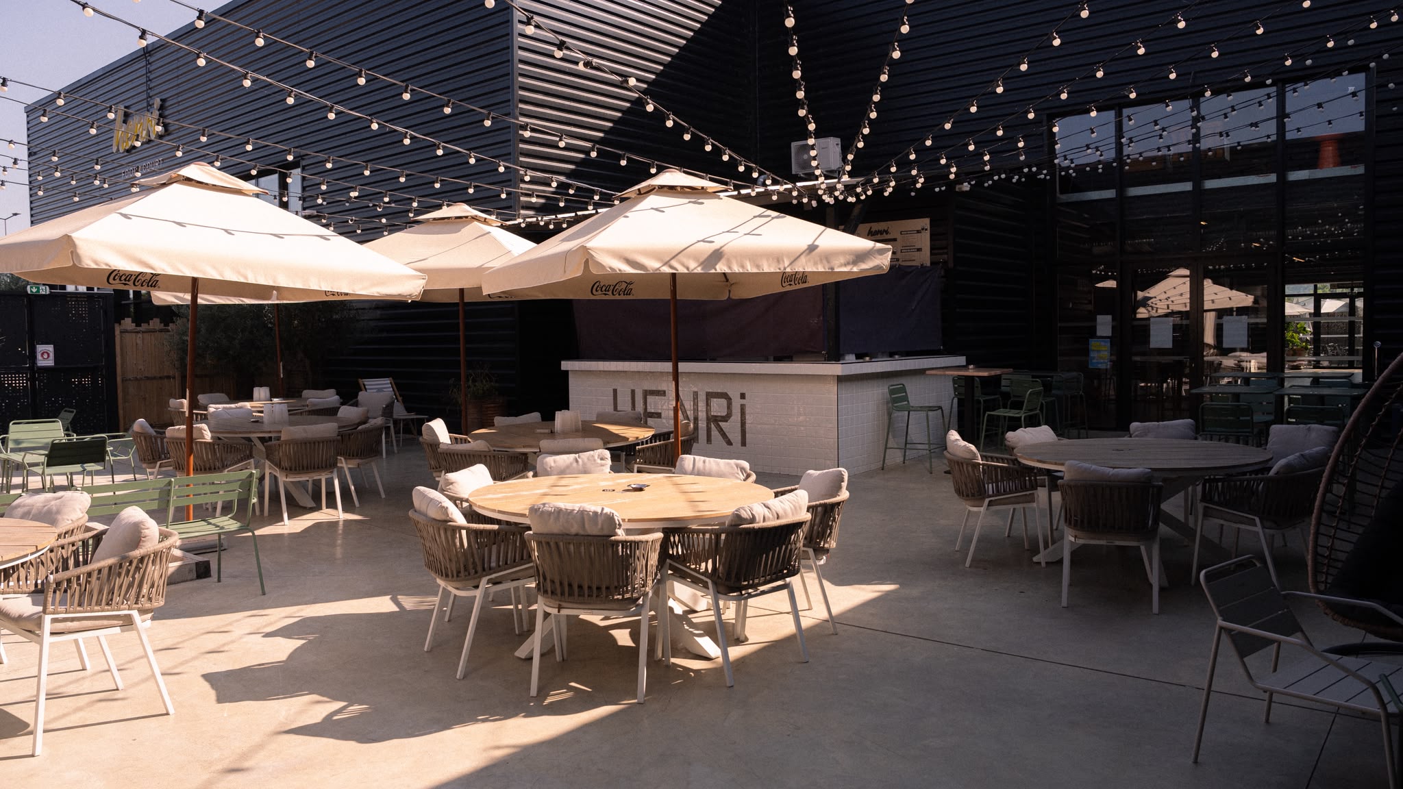 Le Boulodrome du Henri Food Court, terrasse ombragée avec guirlandes lumineuses et tables rondes