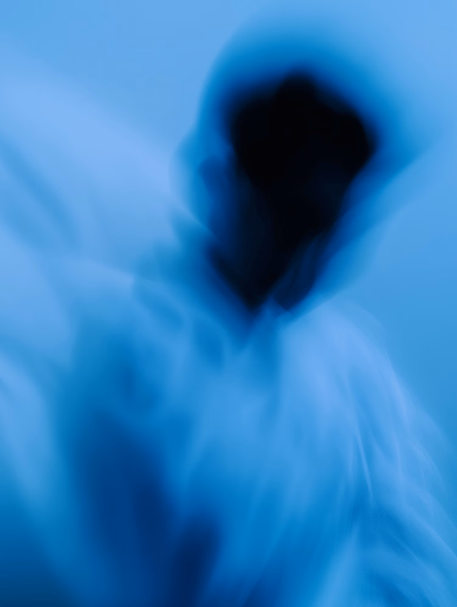 Abstract blurred silhouette of a person in blue tones with an obscured face and form.