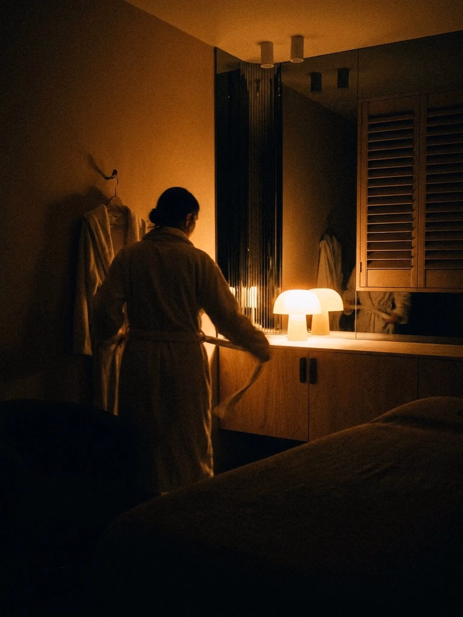 A guest in a VELA robe beside a candlelit bath in a private treatment suite