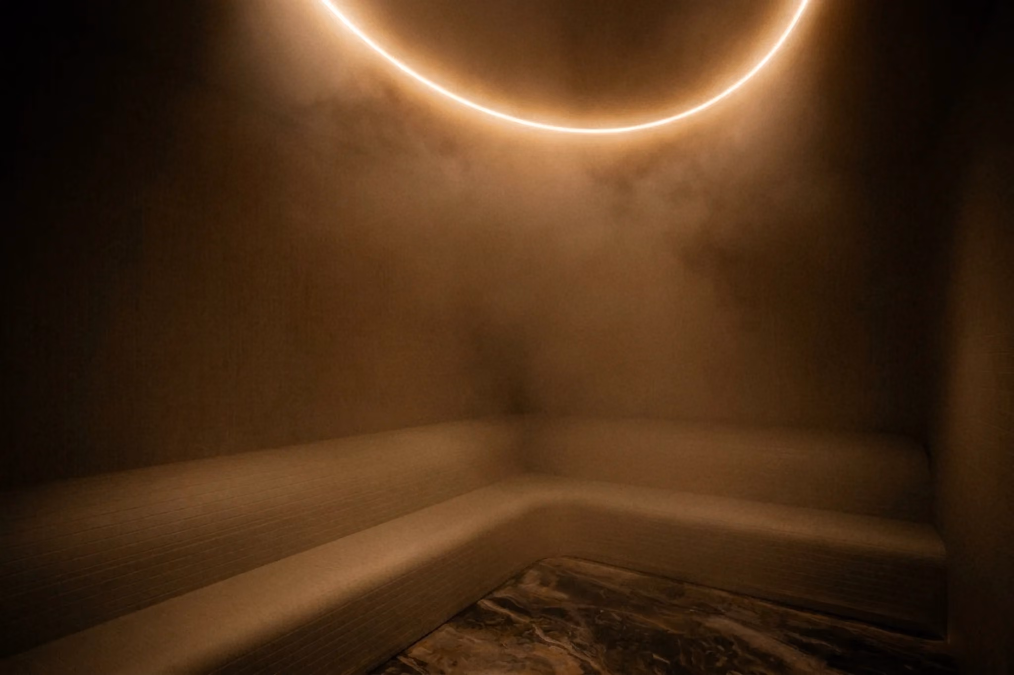 The steam room at VELA Spa & Bathhouse, lit by a circular ceiling light