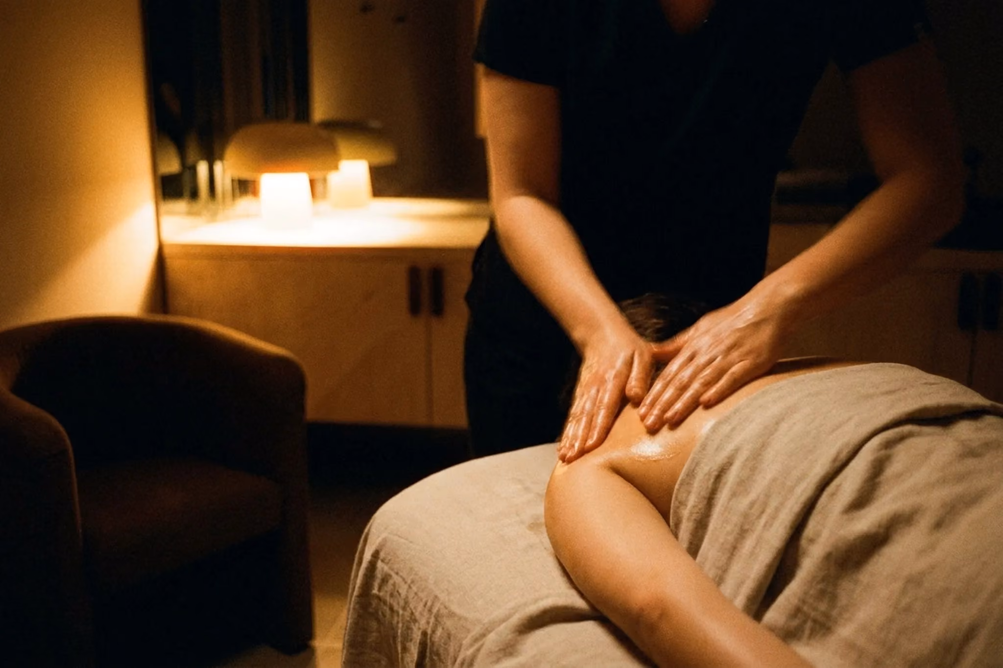A therapist giving a back massage by candlelight at VELA Spa, Windsor NSW