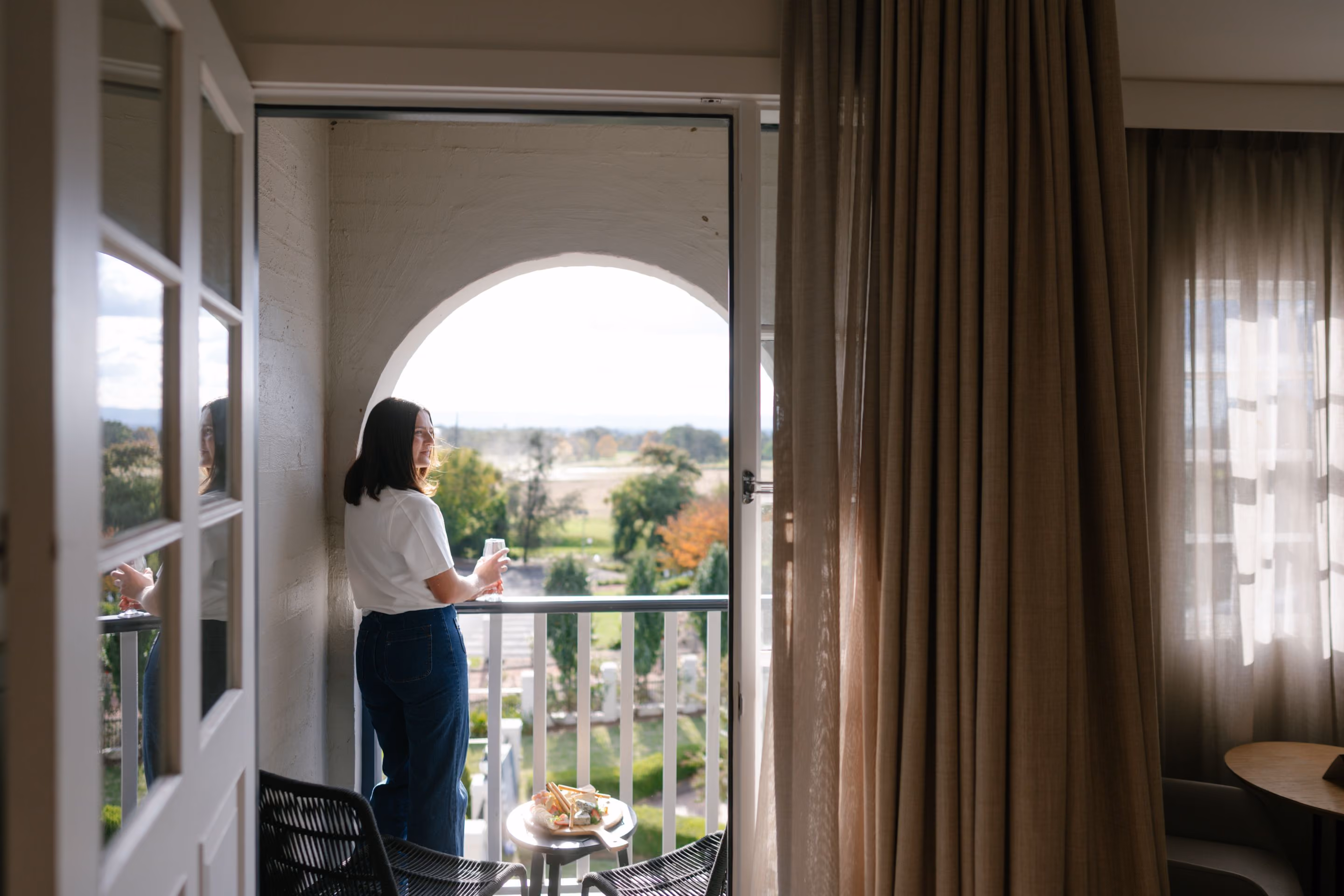 A guest looking out over the gardens from an arched window at VELA