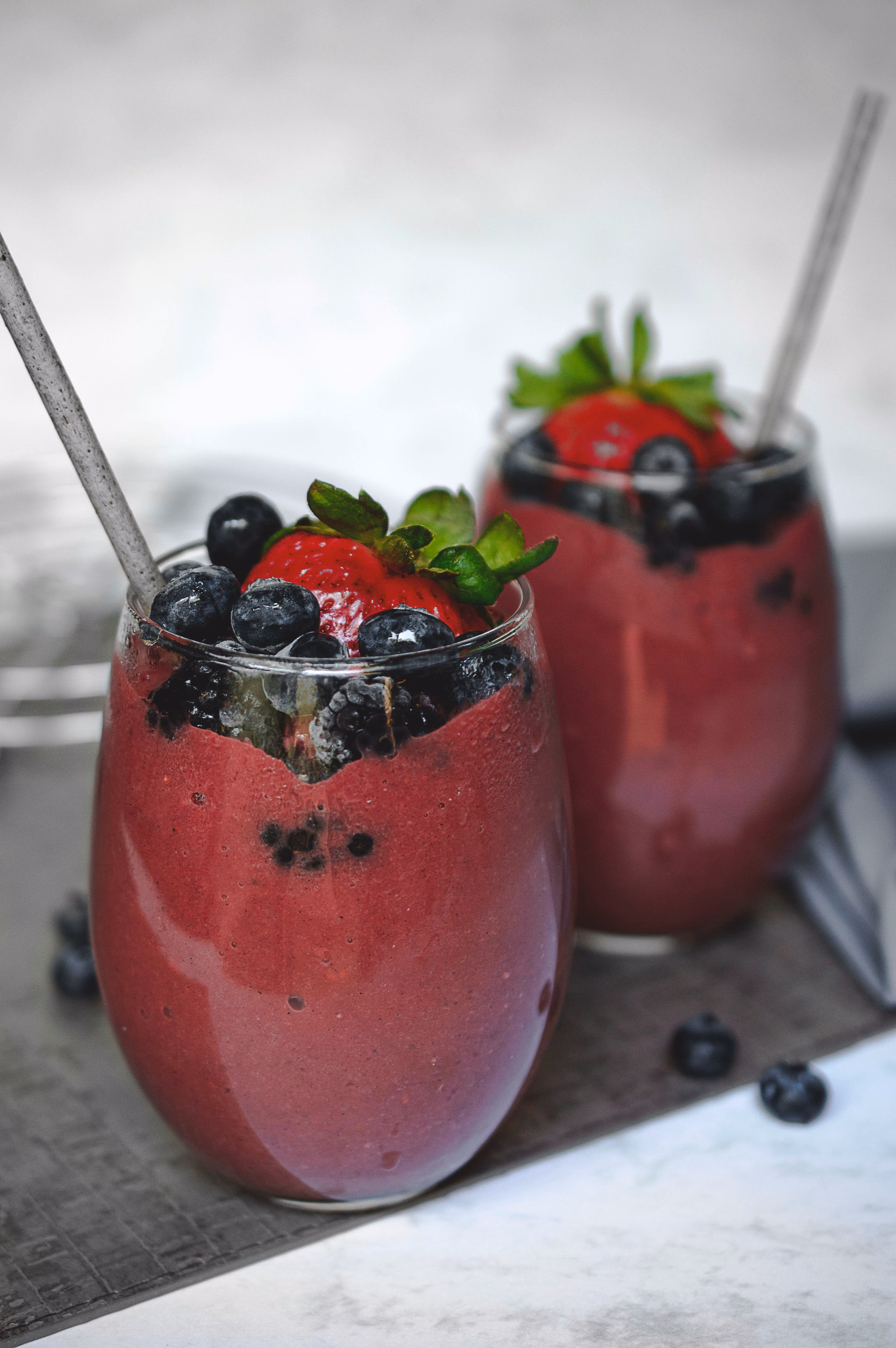 Two berry smoothies topped with fresh fruit from the VELA menu