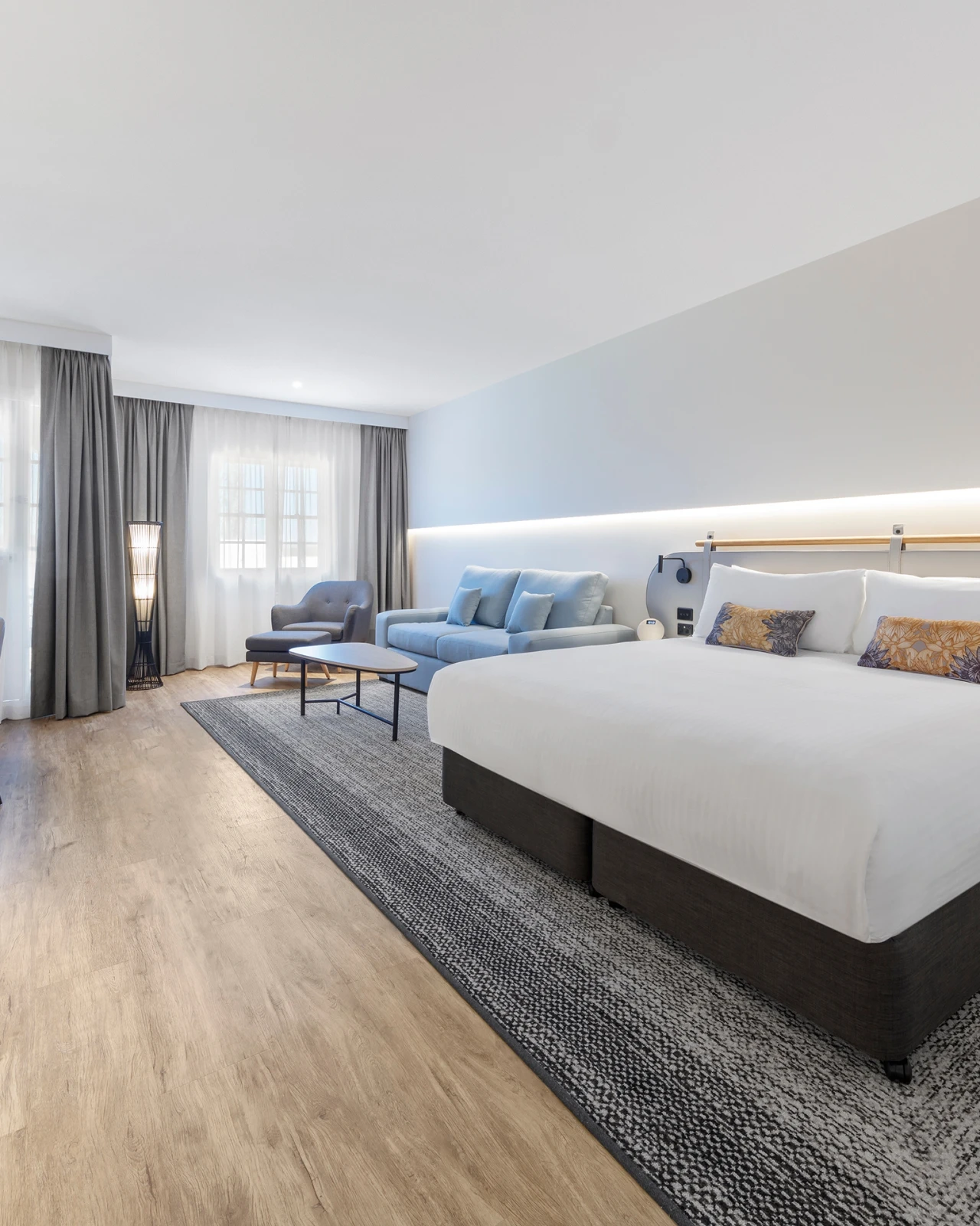 A bright guest room set for an overnight VELA retreat, with a made bed and an armchair by the window