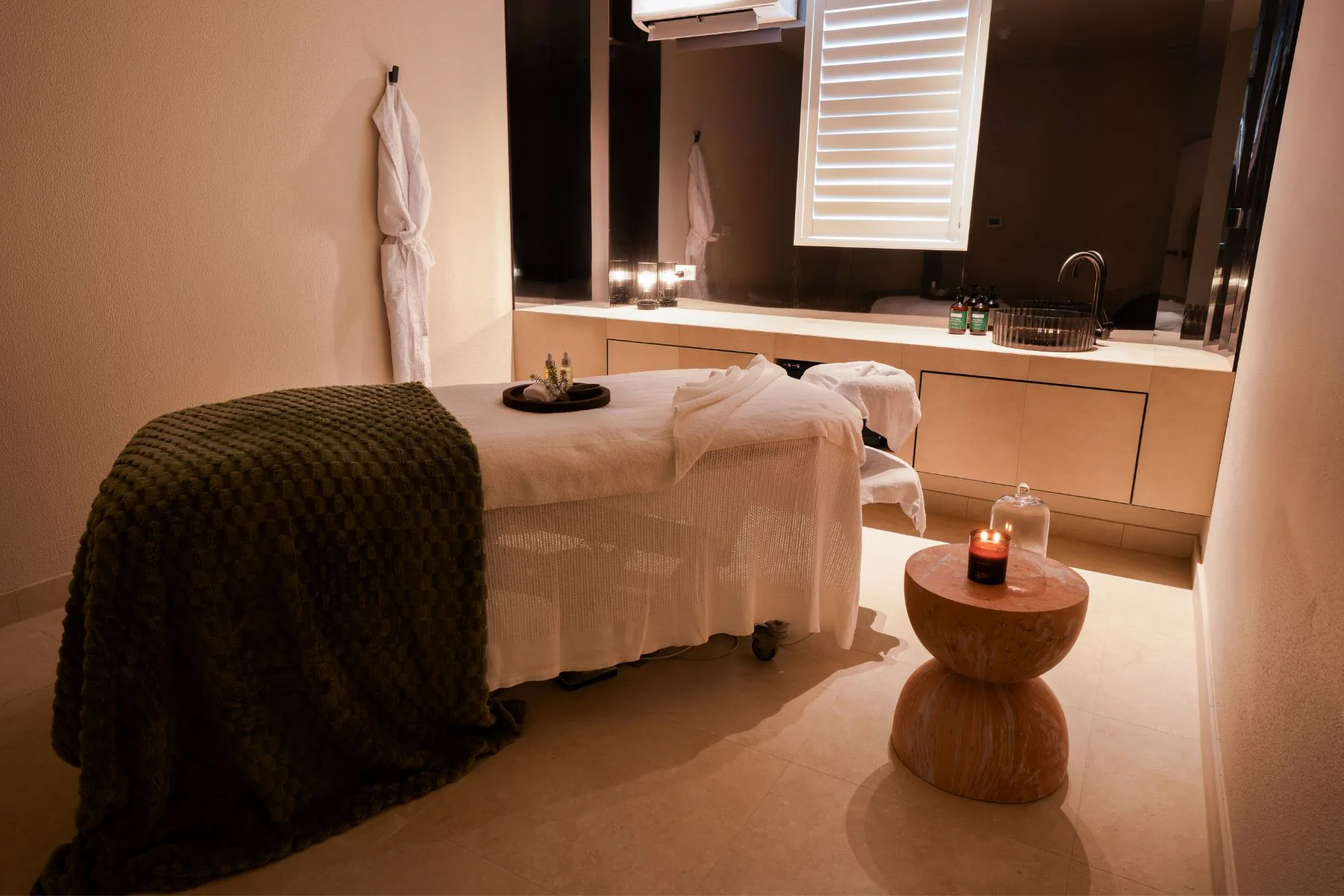 A guest in a VELA robe beside a candlelit bath in a private treatment suite