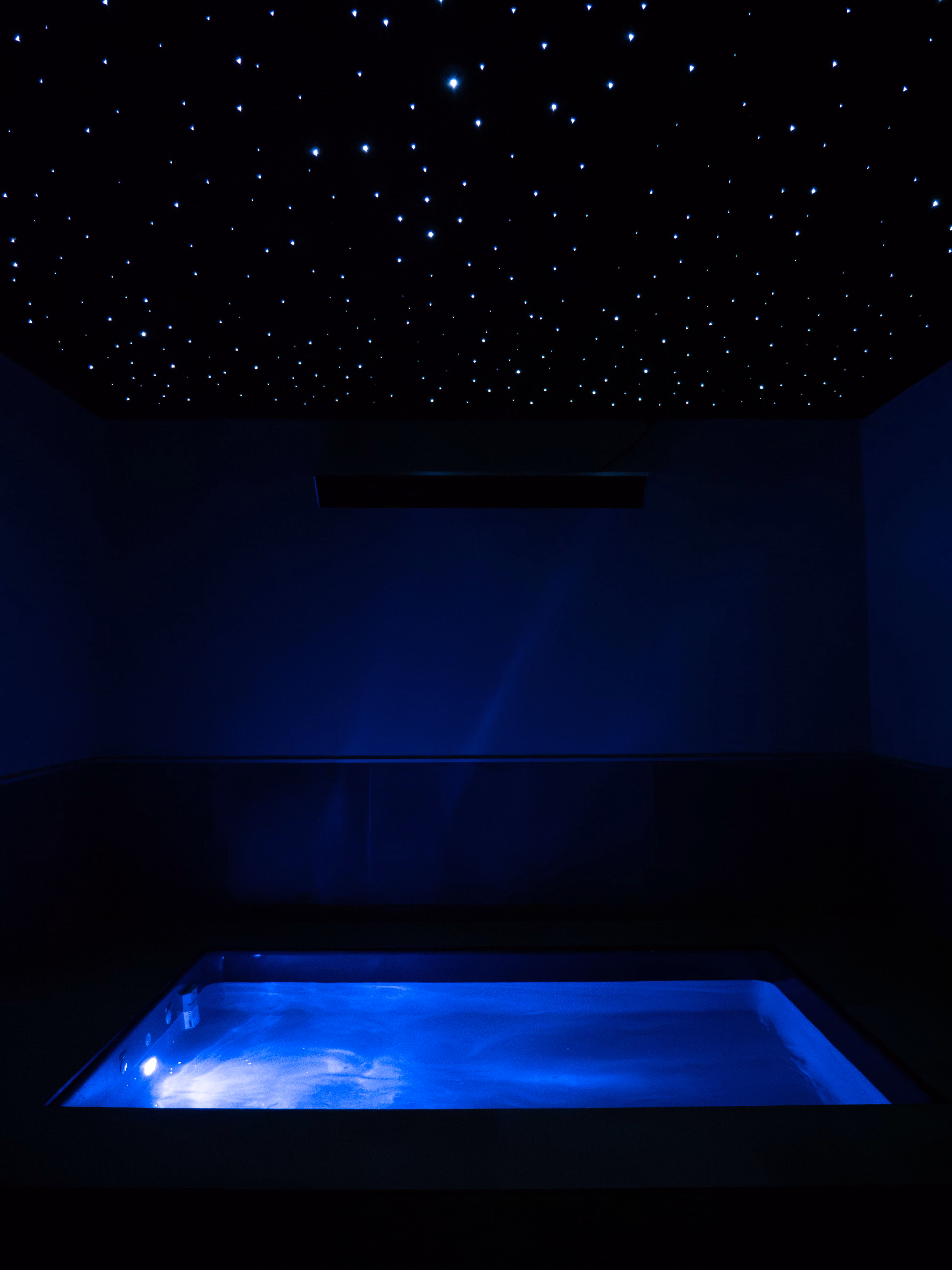 A VELA float room, its turquoise pool lit beneath a ceiling of star lights