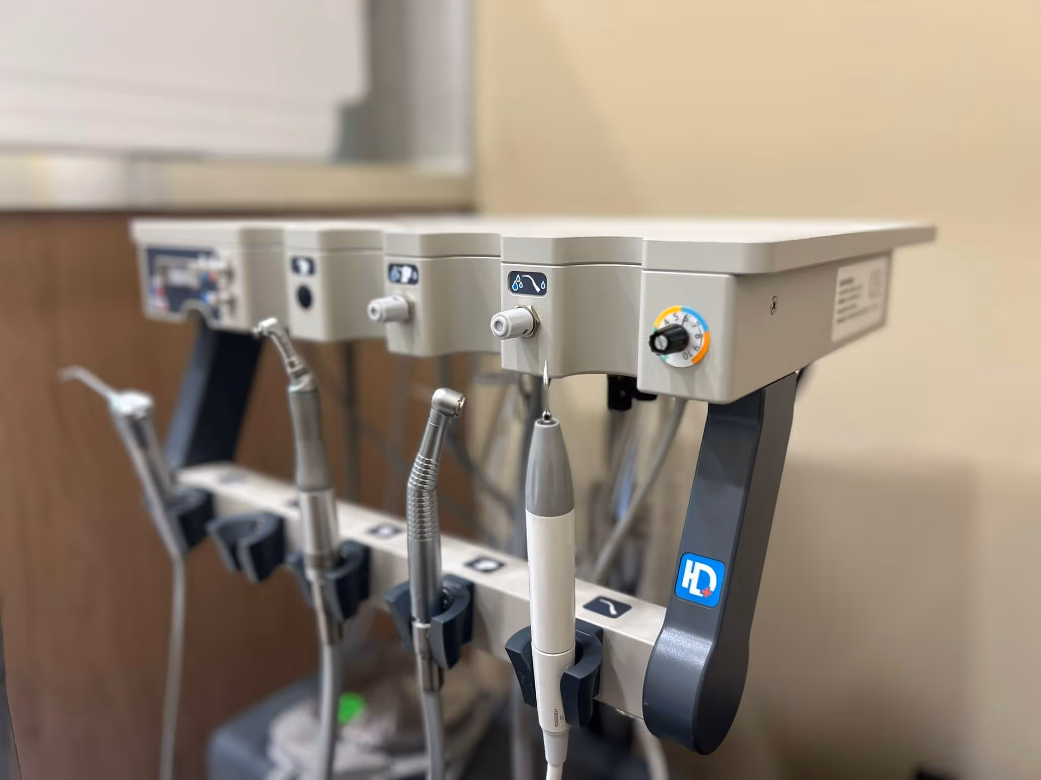 Close-up of dental equipment tools and controls arranged in a row on a beige dental unit.