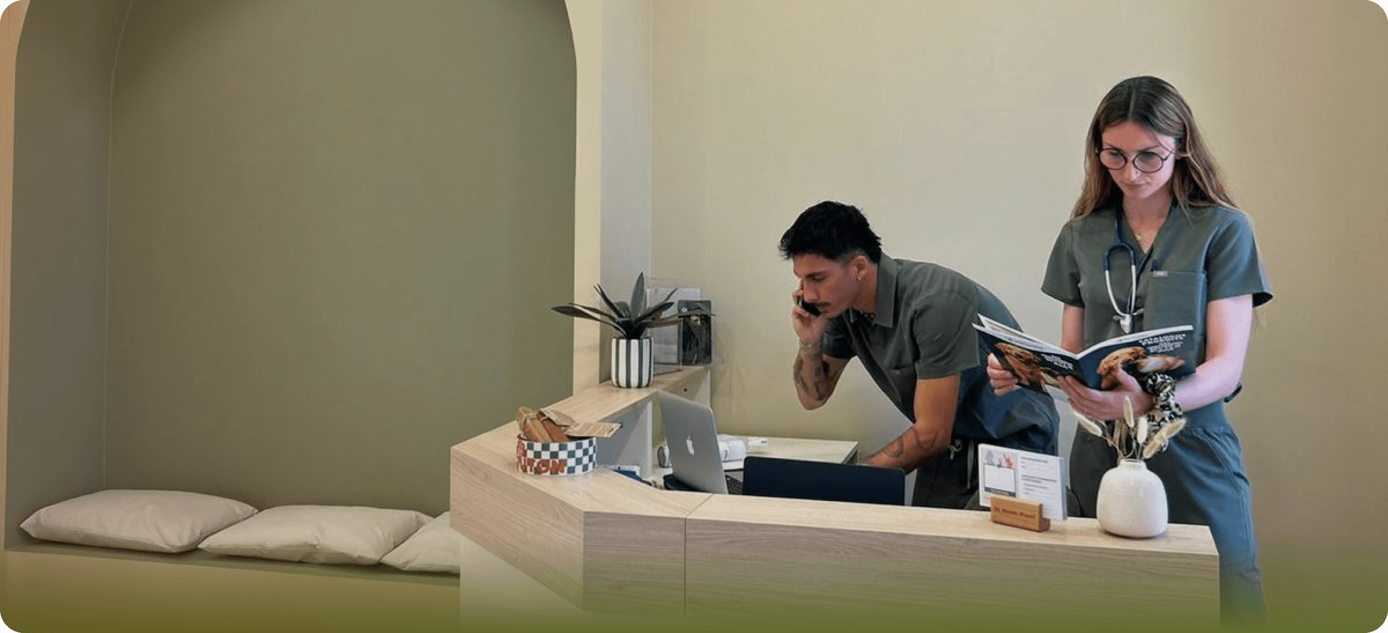 Deux professionnels de santé en uniforme travaillant à un bureau avec un ordinateur et un livre.