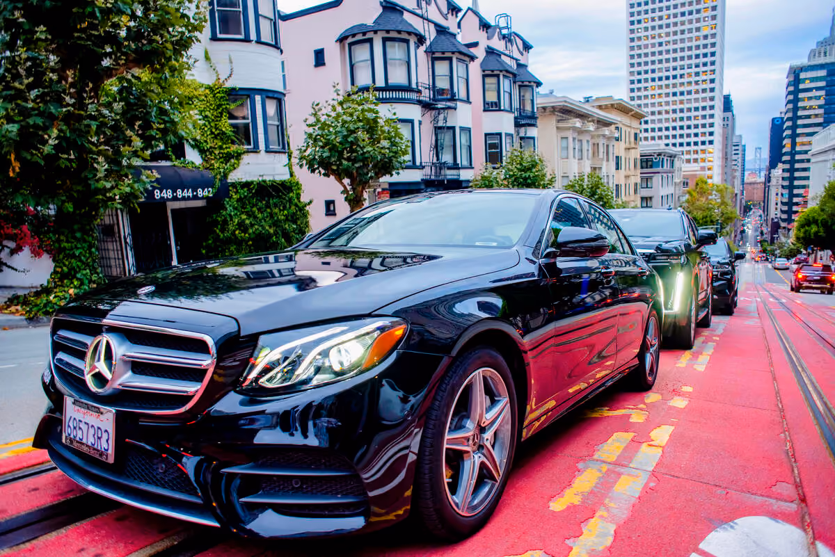 Black Mercedes sedan parked in a red transit lane with Victorian style houses behind