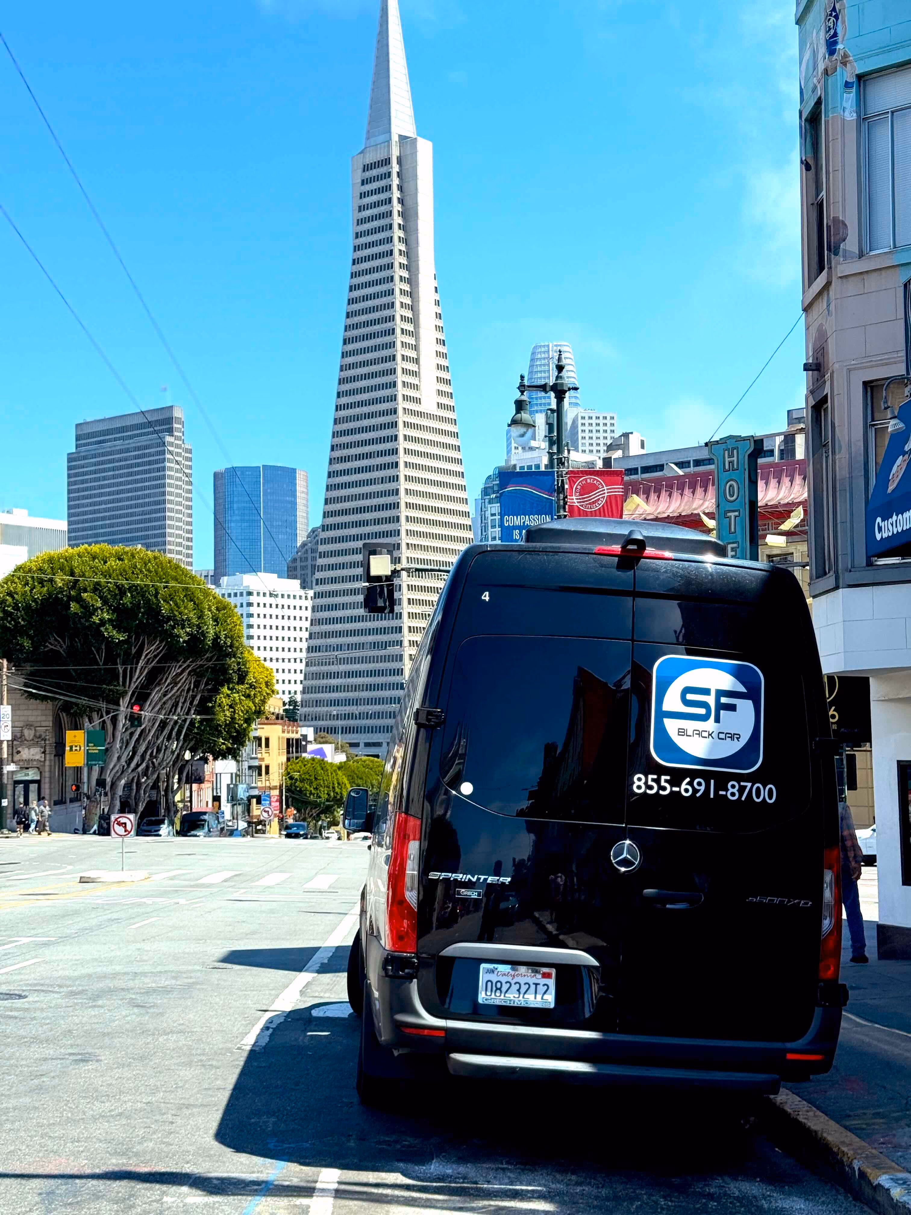 Rear of a black Mercedes Sprinter van parked on a city street with a pyramid shaped skyscraper behind