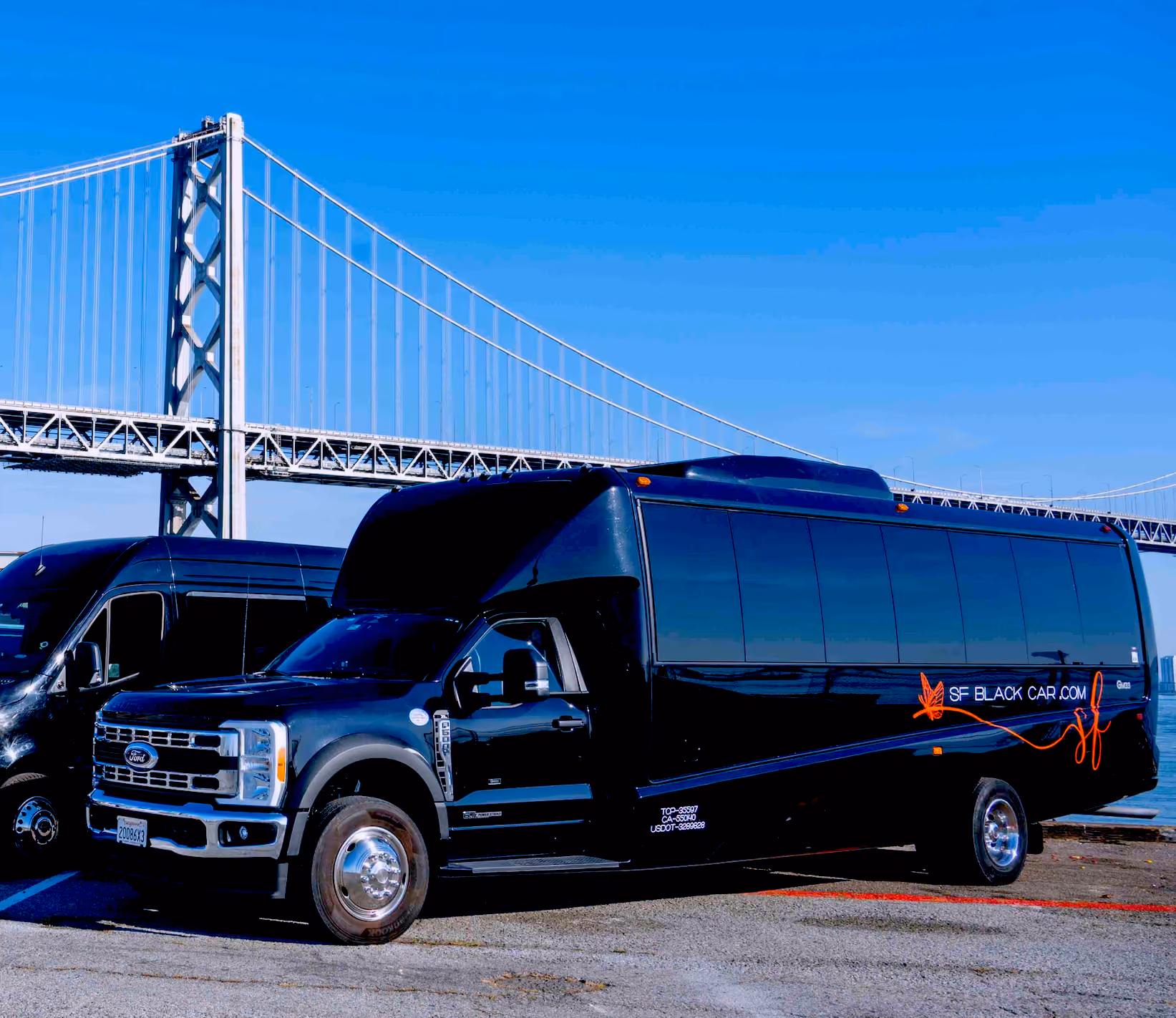 Black minibus with SF Black Car logo parked on a waterfront lot with a suspension bridge behind
