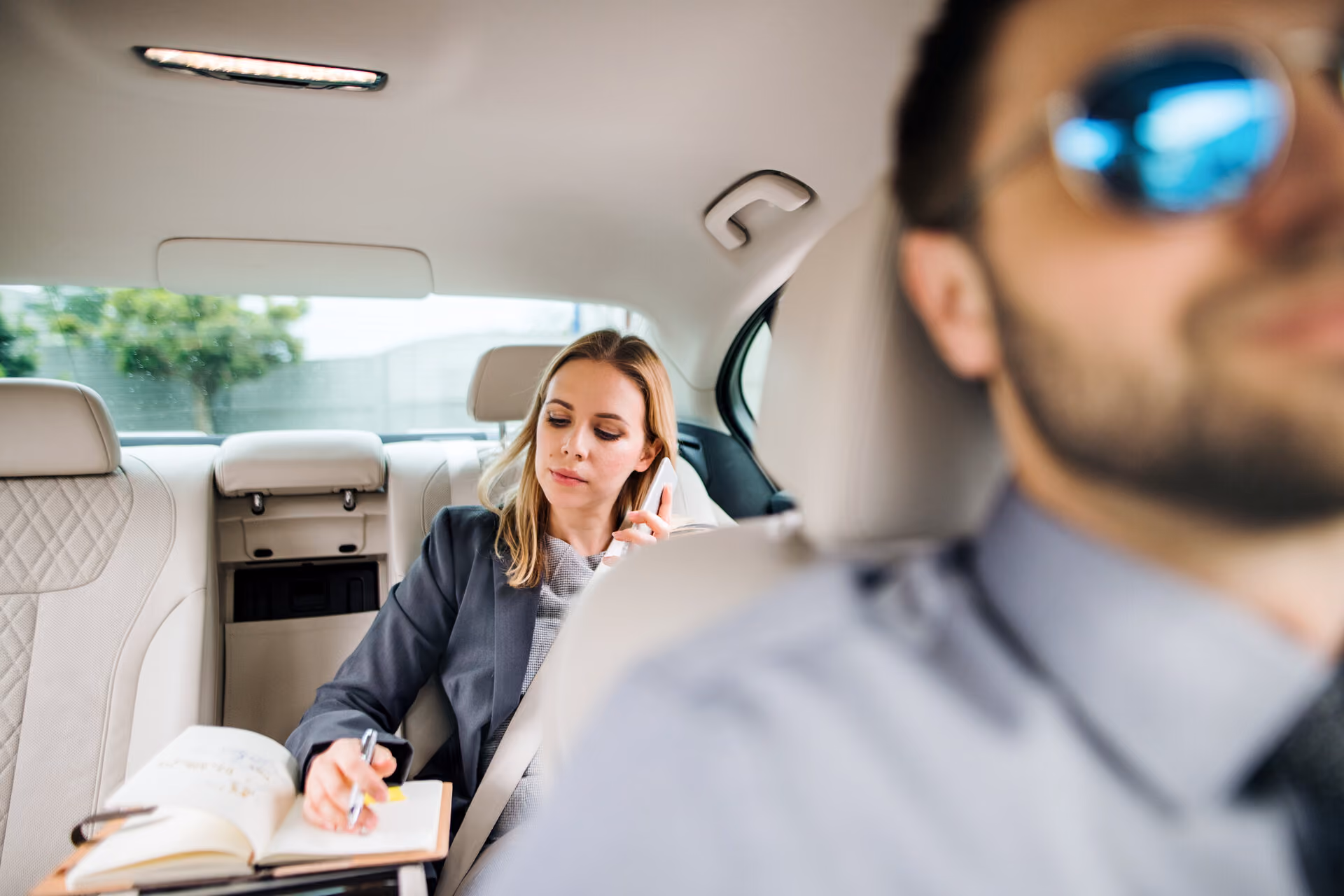 Businesswoman working on a phone call in the back seat of a car