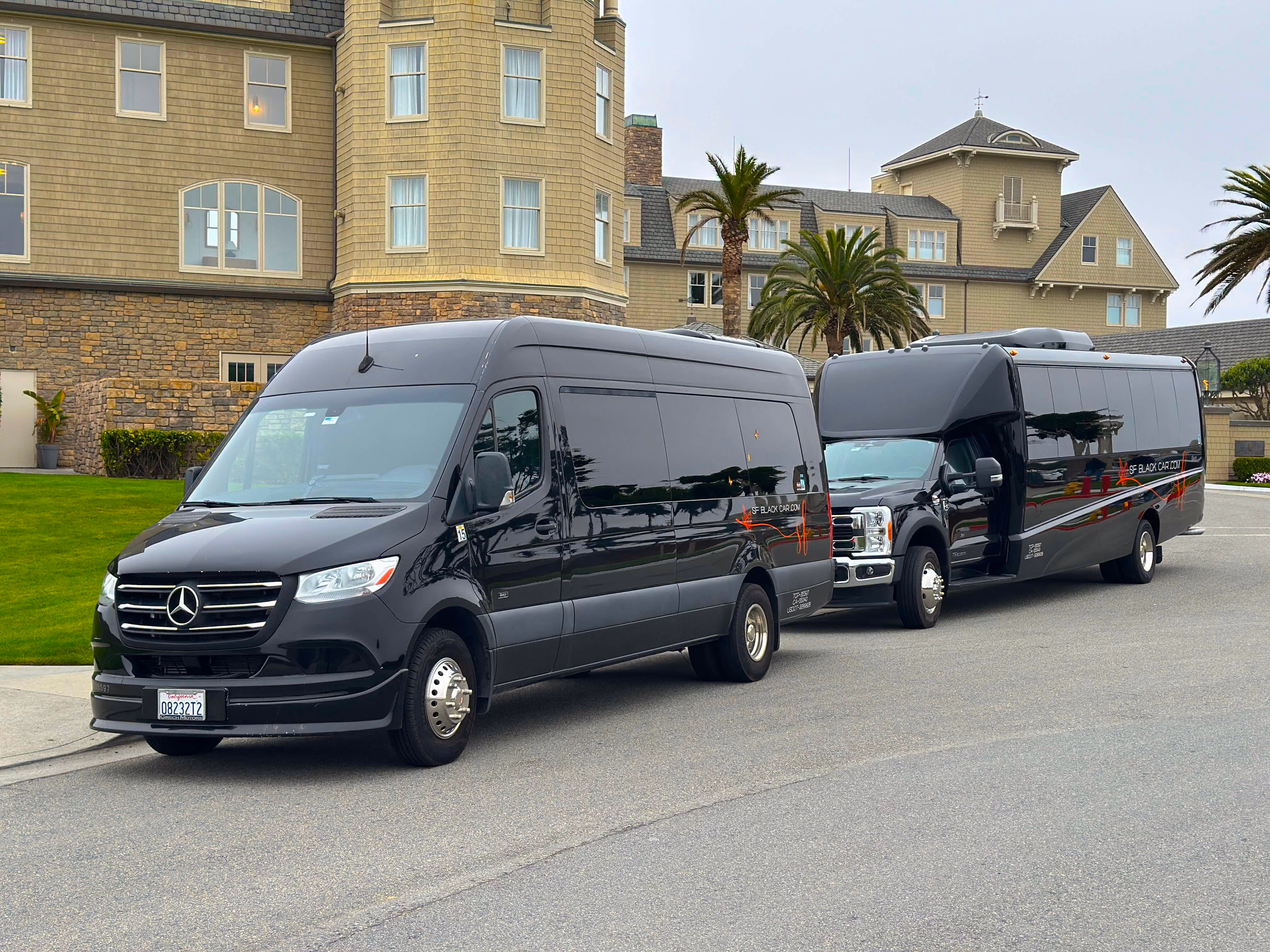Black Mercedes Sprinter van and a black mini coach bus parked in front of a large seaside hotel