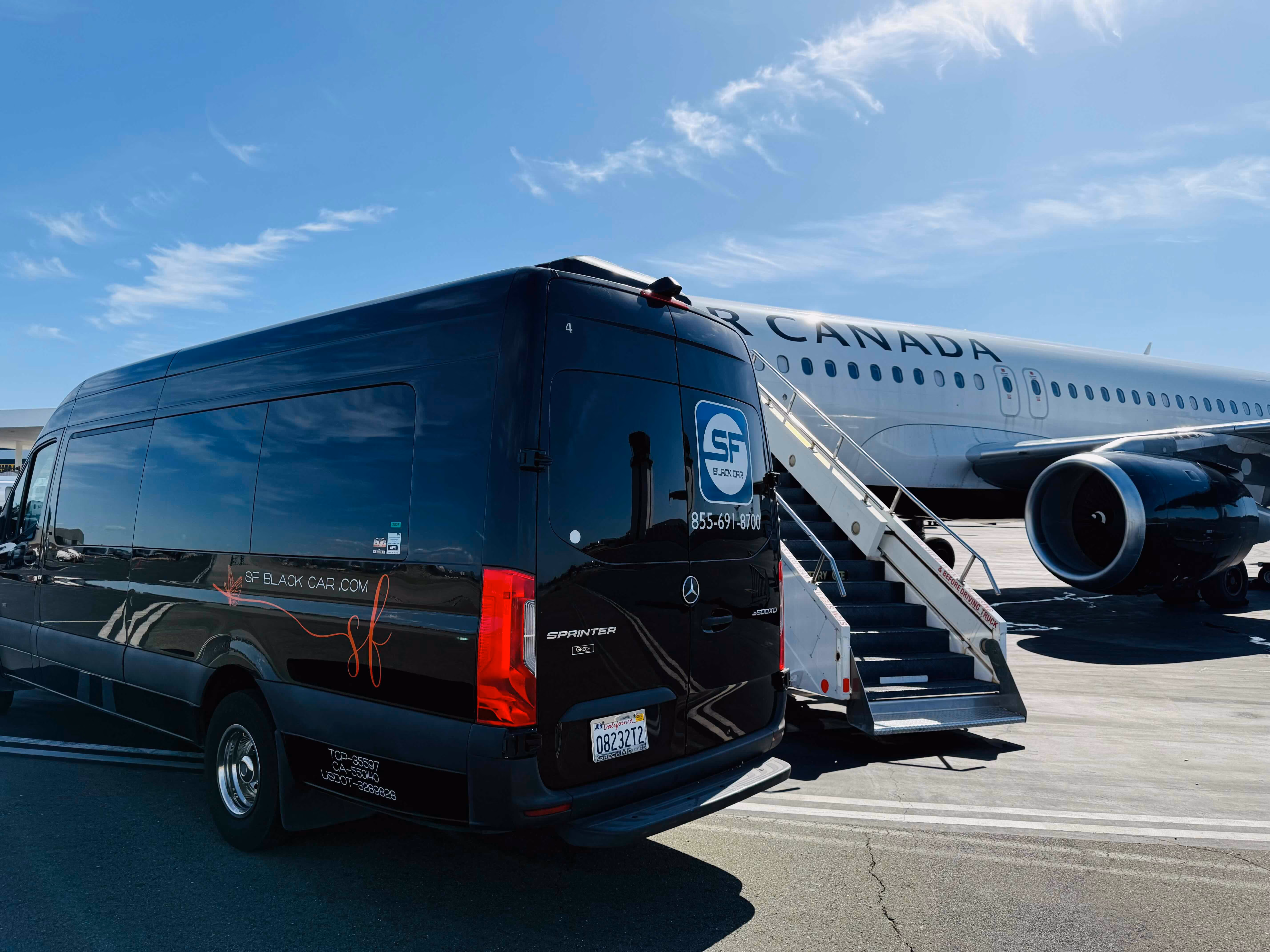 Black SF Black Car Sprinter van parked beside an Air Canada aircraft with boarding stairs on the tarmac
