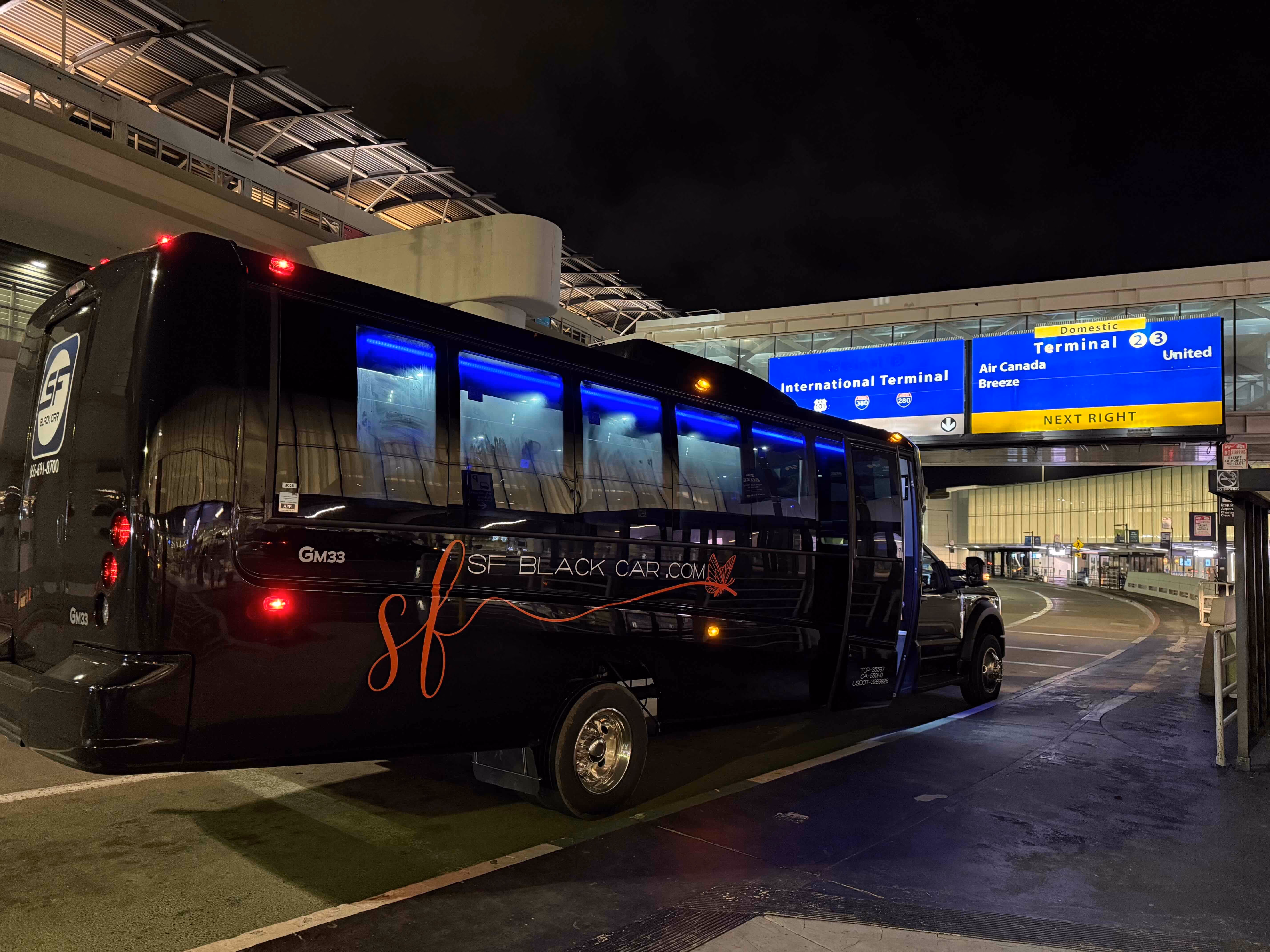 Black SF Black Car mini coach bus parked at the International Terminal at night