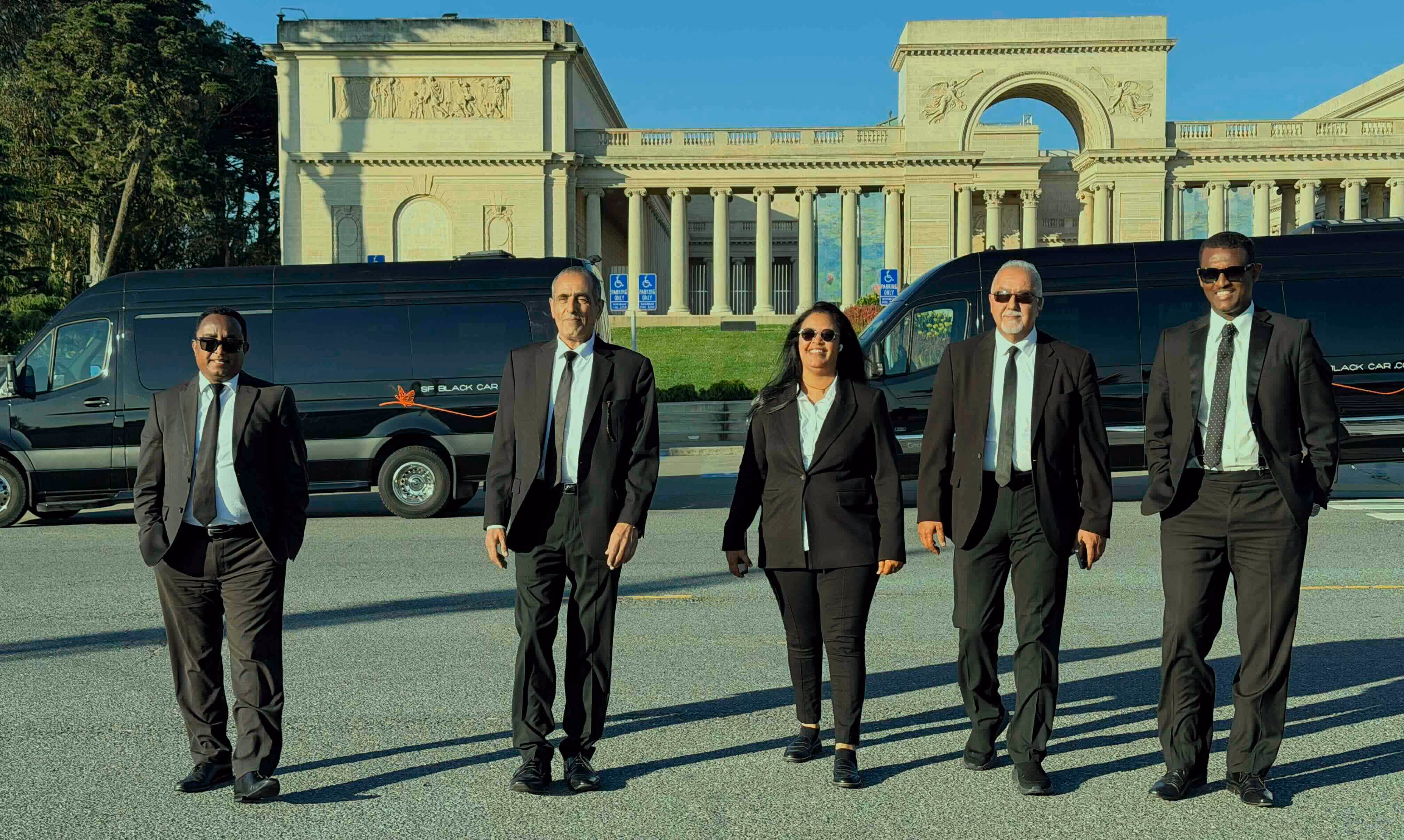 Five SF Black Car chauffeurs in dark suits standing in front of black vans at the Legion of Honor in San Francisco