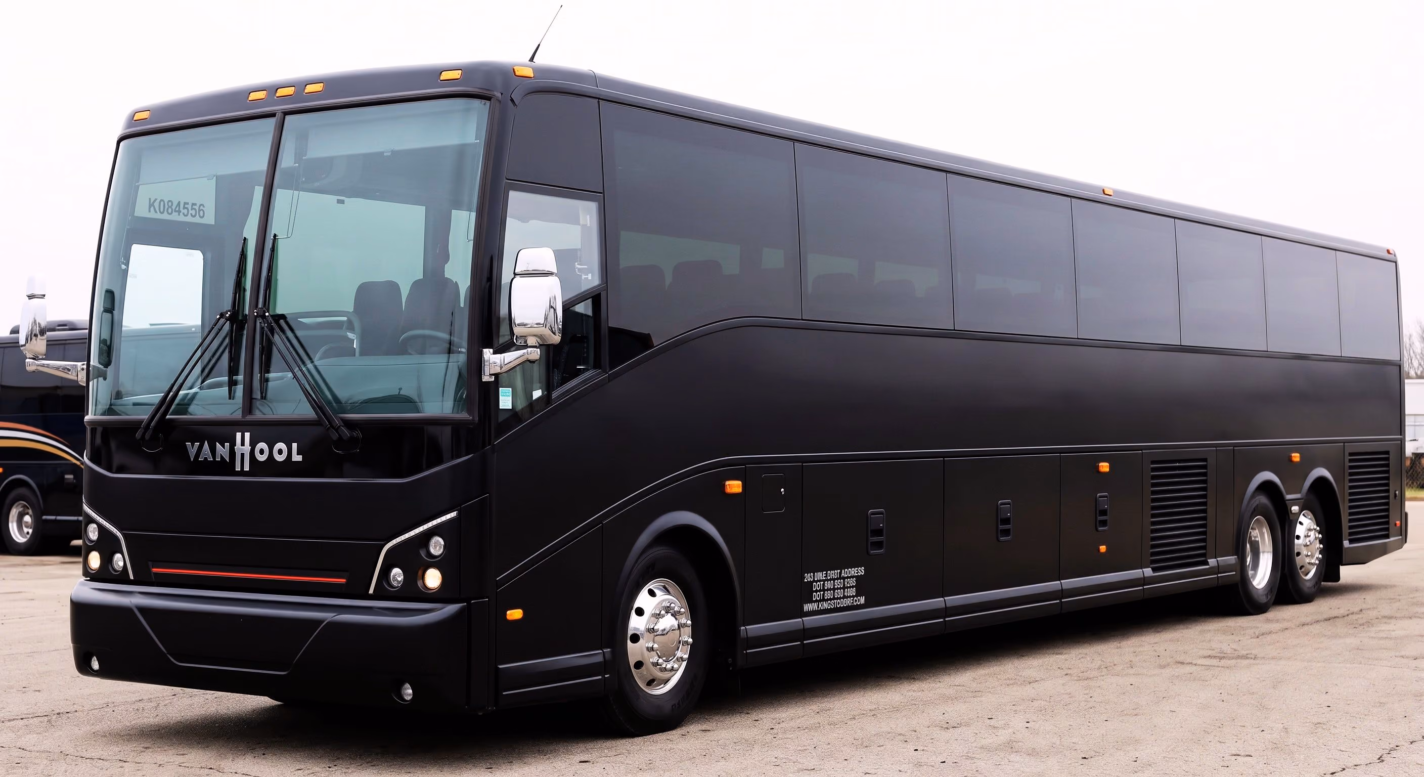 Black Van Hool coach bus parked on pavement with tinted windows and silver hubcaps.