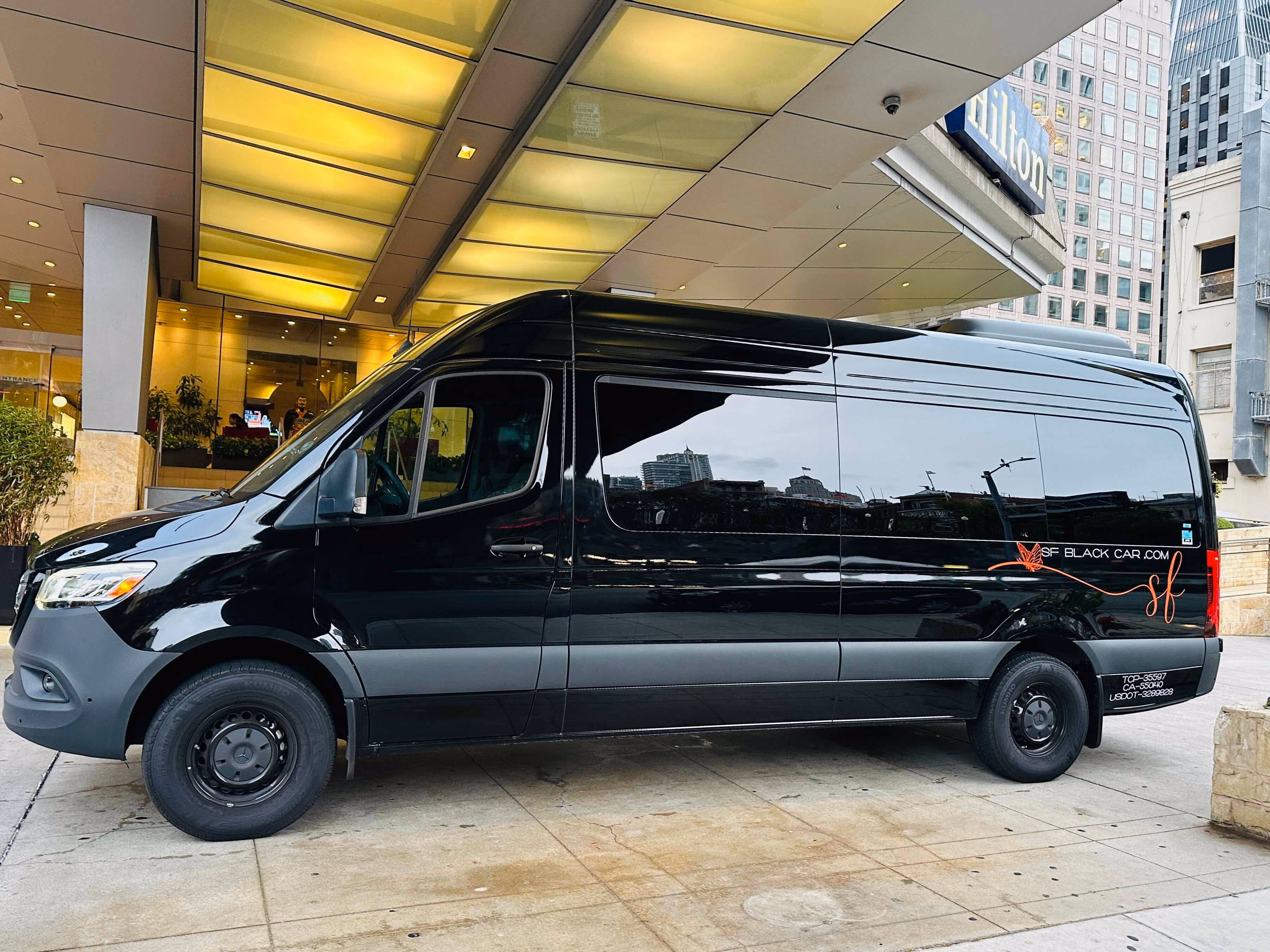 Black SF Black Car Sprinter van parked under a building overhang downtown